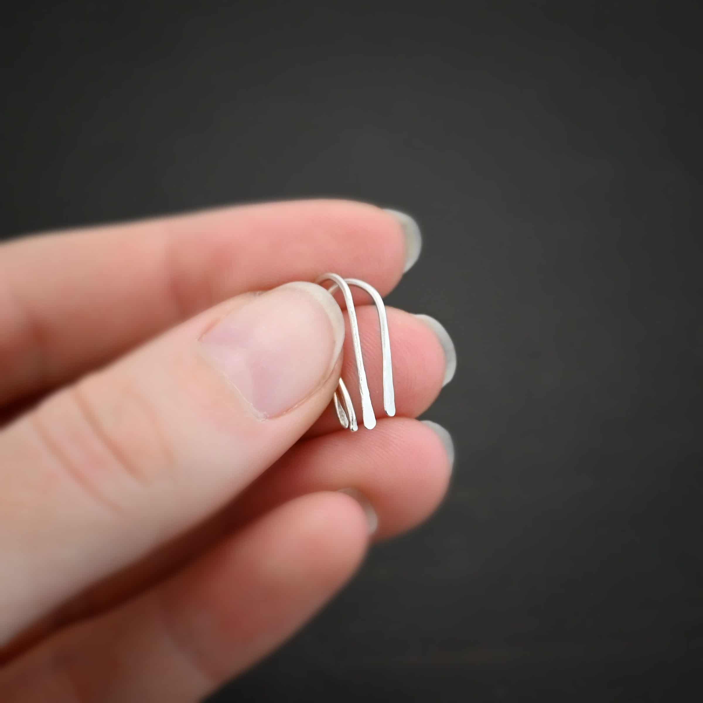Roadies Photo of the "Roadie" Earrings. Made out of sterling silver. Earrings are very simple. They are an ear wire with one end lightly hammered and tipped and the other end of the earring is a hammered paddle. Earrings are held in the fingertips of a hand.
