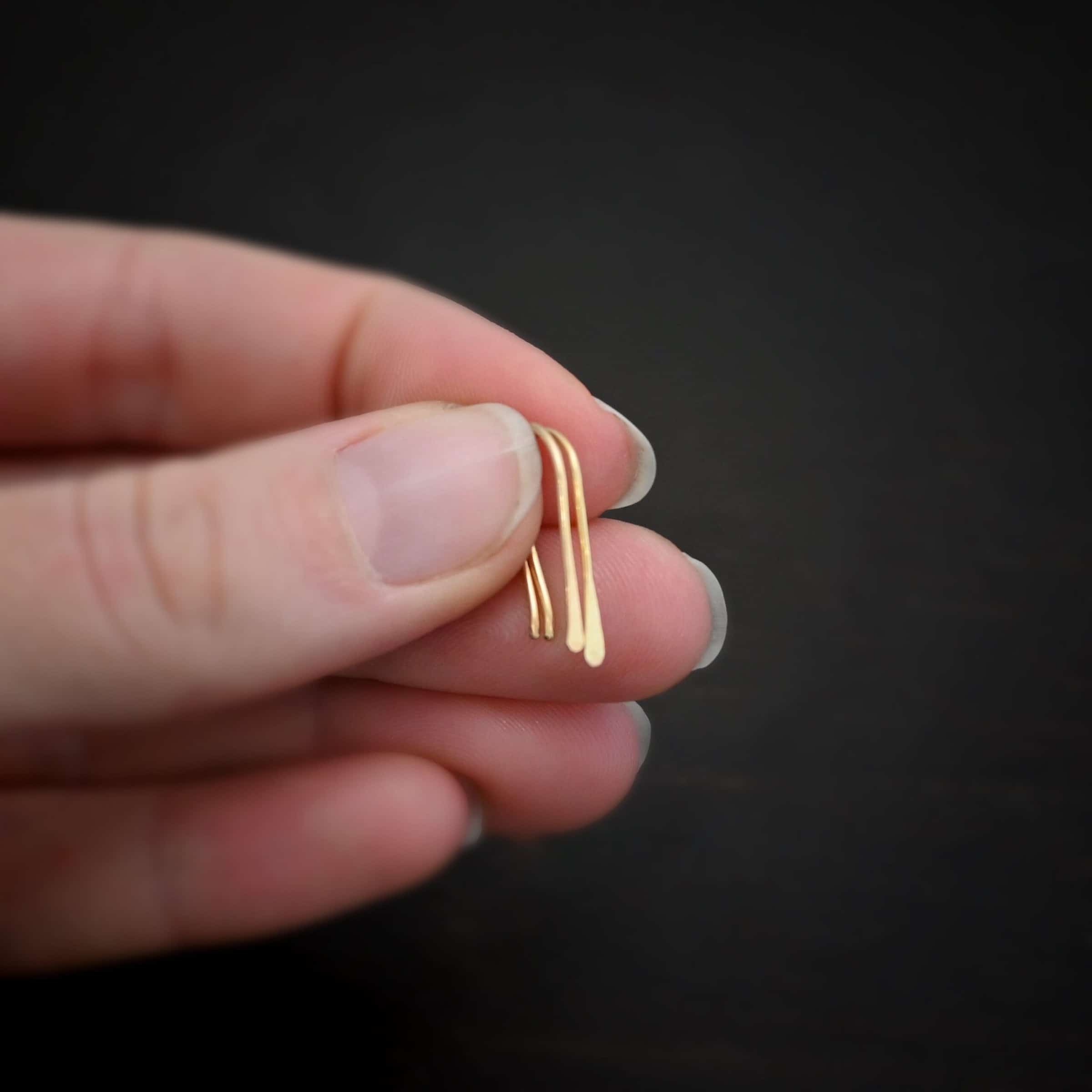 Roadies Photo of the "Roadie" Earrings. Made out of 14k gold. Earrings are very simple. They are an ear wire with one end lightly hammered and tipped and the other end of the earring is a hammered paddle. Earrings are held in the fingertips of a hand.