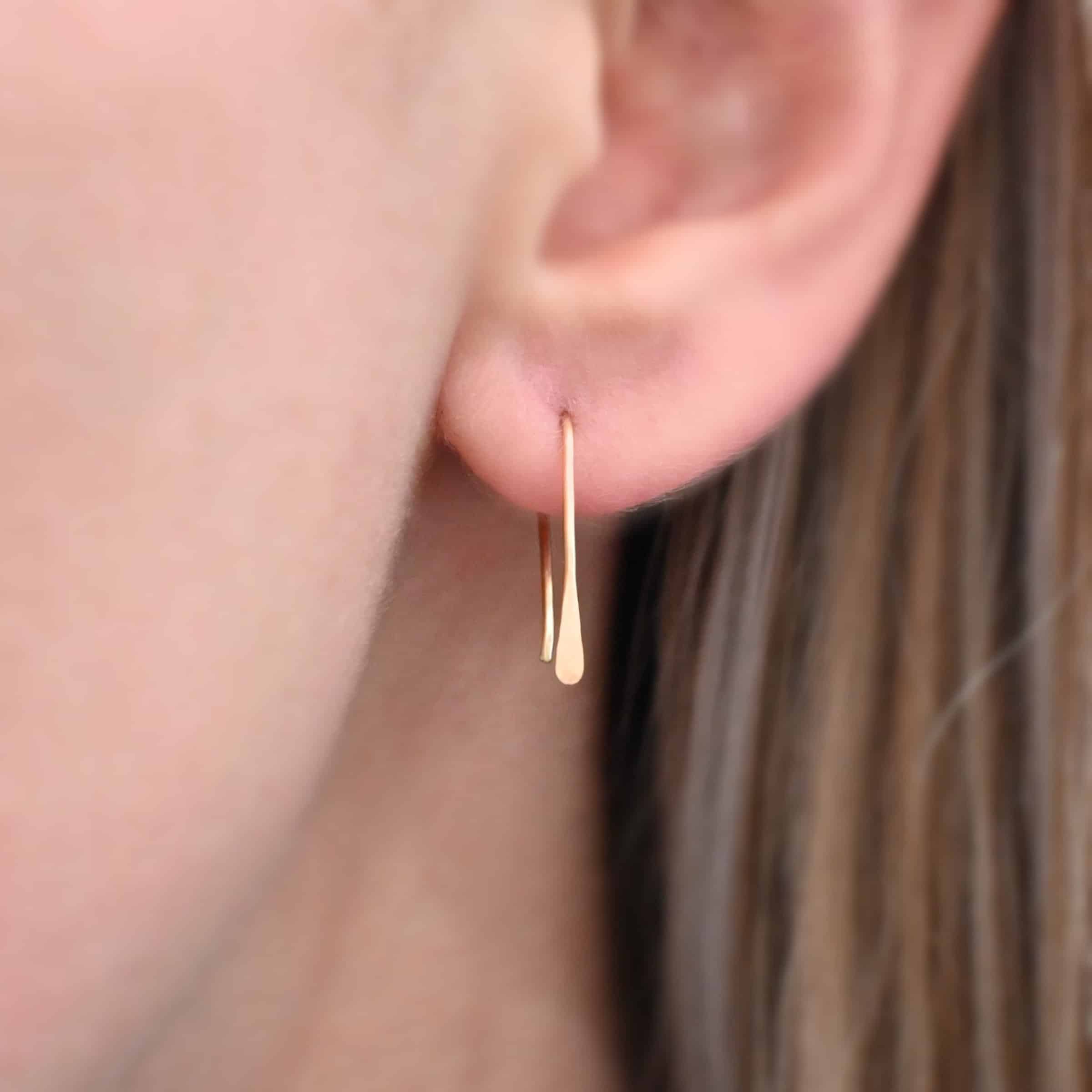 Roadies Photo of the "Roadie" Earring up close by a model. Made out of 14k gold. Earrings are very simple. They are an ear wire with one end lightly hammered and tipped and the other end of the earring is a hammered paddle.