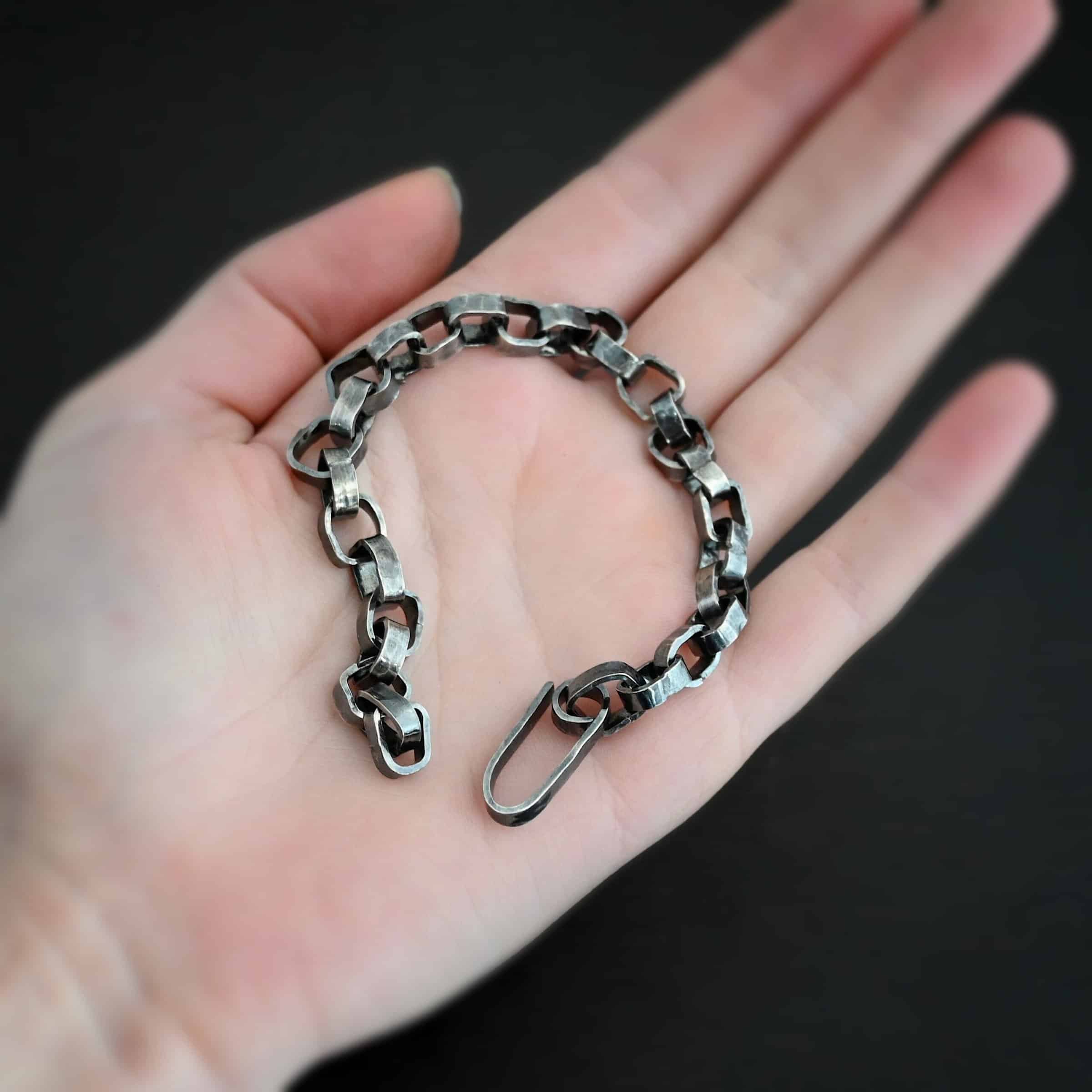 Rustic Bracelet Photo of the "Rustic" Bracelet. Bracelet is made out of sterling silver. Each link is a thick circle link that is hammered and oxidized. The clasp of the bracelet is also thick, hammered, and oxidized, but it is a long oval shape. Bracelet is lying on the palm of a hand.