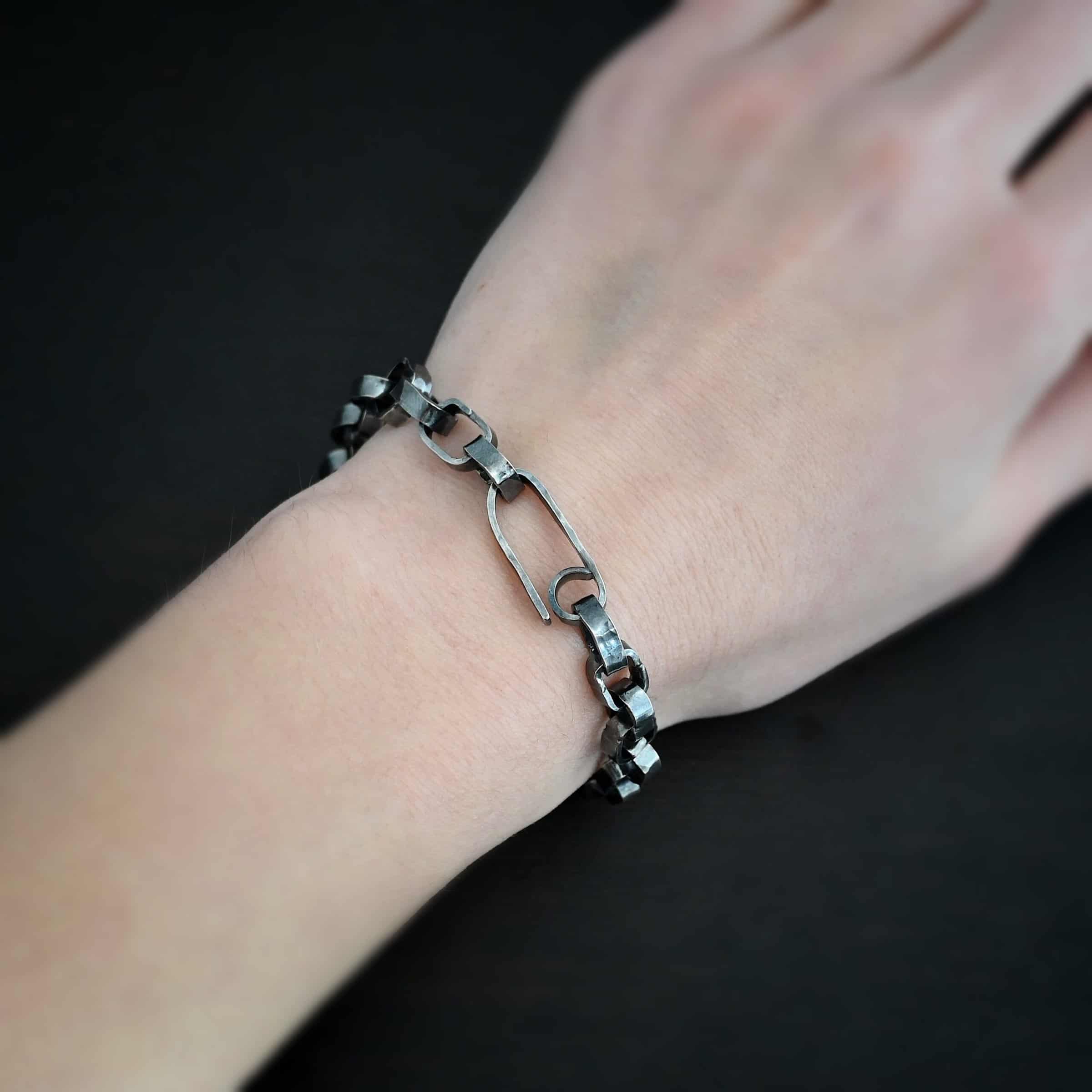 Rustic Bracelet Photo of the "Rustic" Bracelet. Bracelet is made out of sterling silver. Each link is a thick circle link that is hammered and oxidized. The clasp of the bracelet is also thick, hammered, and oxidized, but it is a long oval shape. Bracelet is worn by a model.