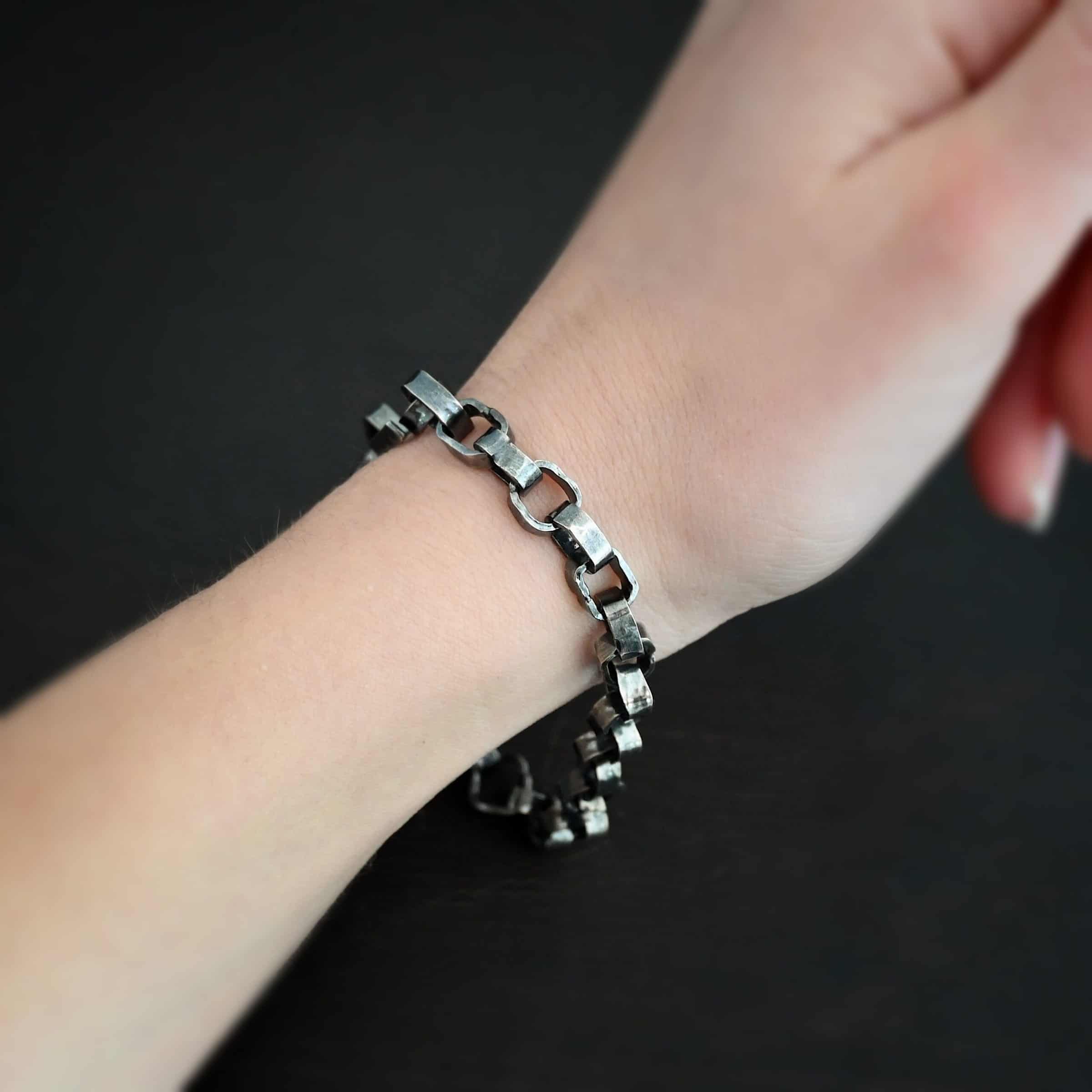 Rustic Bracelet Photo of the "Rustic" Bracelet. Bracelet is made out of sterling silver. Each link is a thick circle link that is hammered and oxidized. The clasp of the bracelet is also thick, hammered, and oxidized, but it is a long oval shape. Bracelet is worn by a model.
