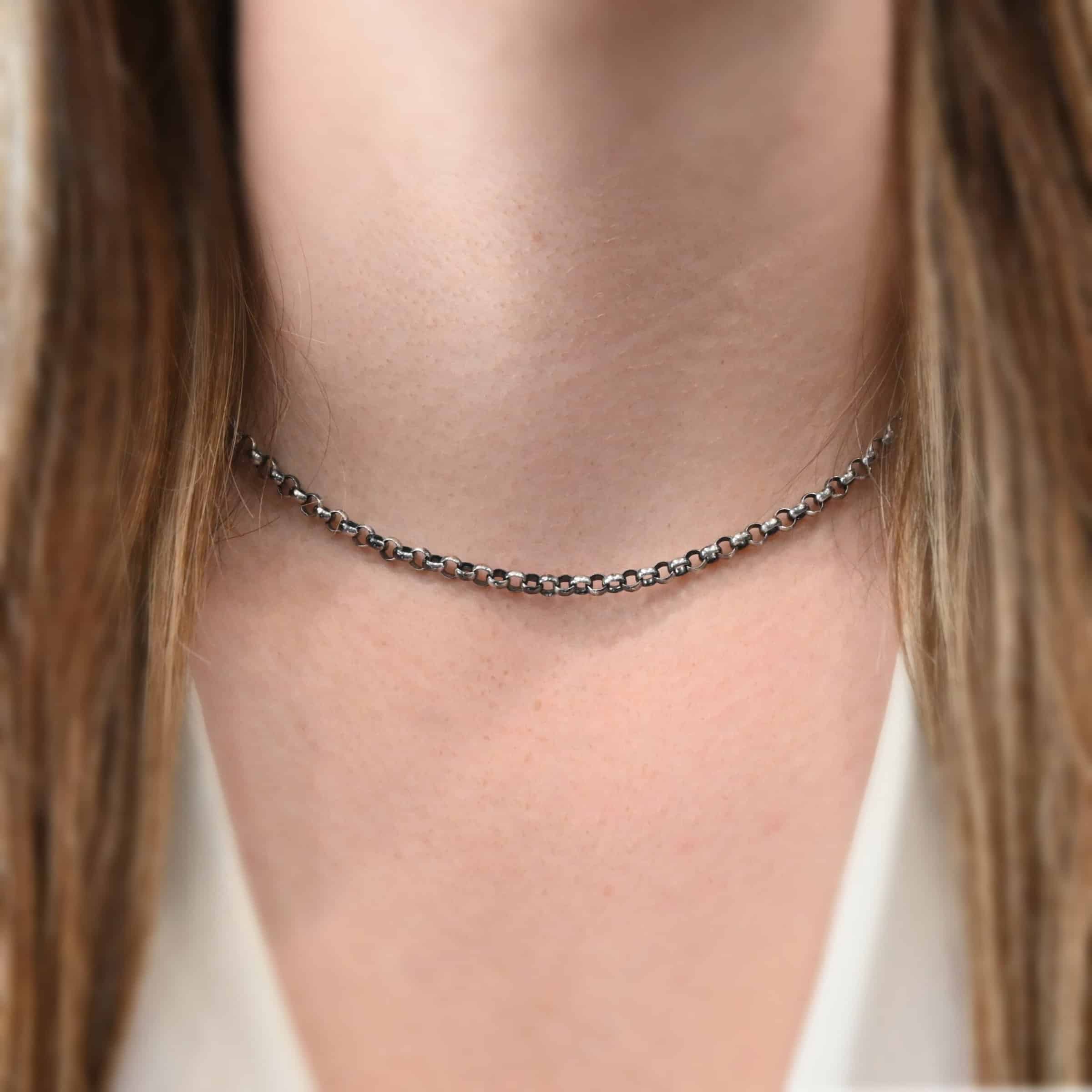 Close up of the "Roxy Rolo" Chain as shown on a model. Chain is shown as oxidized and 16" long. Model is wearing a white v-neck shirt. Heavy Rolo links measure 4.25mm.