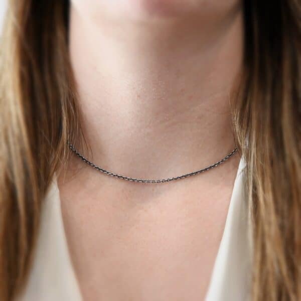 "Savannah" Chain as shown on a model. Links are 3x2mmx.7mm thick. Chain is shown on a model at 16" long and oxidized. Model is wearing a white v-neck shirt.