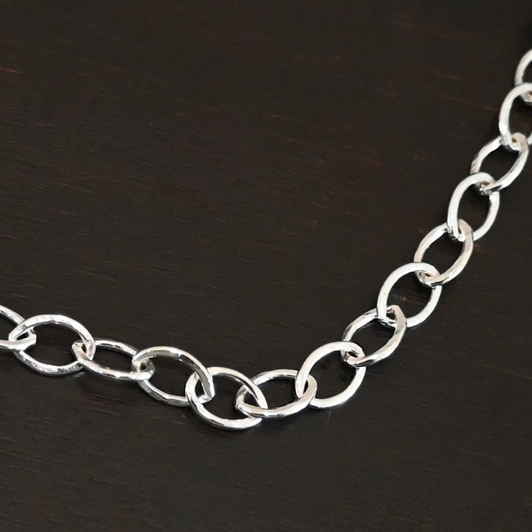 Sky Chain Hammered The "Sky" Chain. Shown as hammered, and shiny. Handmade links that are made out of sterling silver and connected to each other. Chain is laying against a dark background.