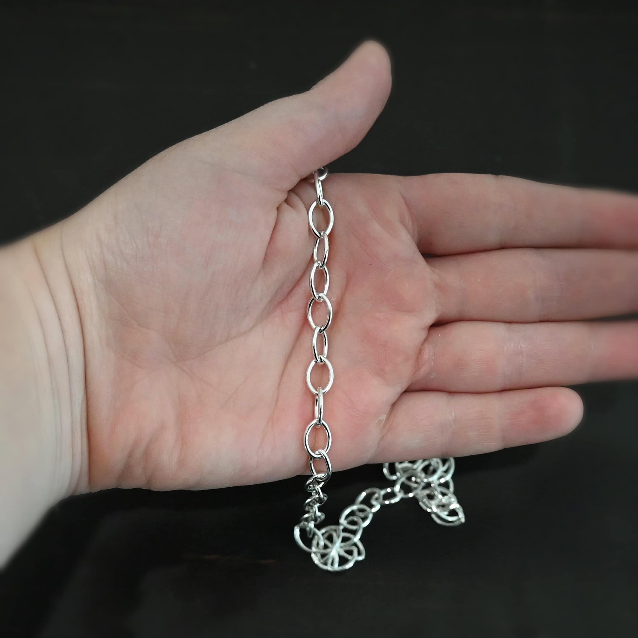 Sky Chain Smooth The "Sky" Chain. Shown as smooth, and shiny. Handmade links that are made out of sterling silver and connected to each other. Comes with a S hook clasp. Chain is laying against a the palm of a hand to demonstrate size.