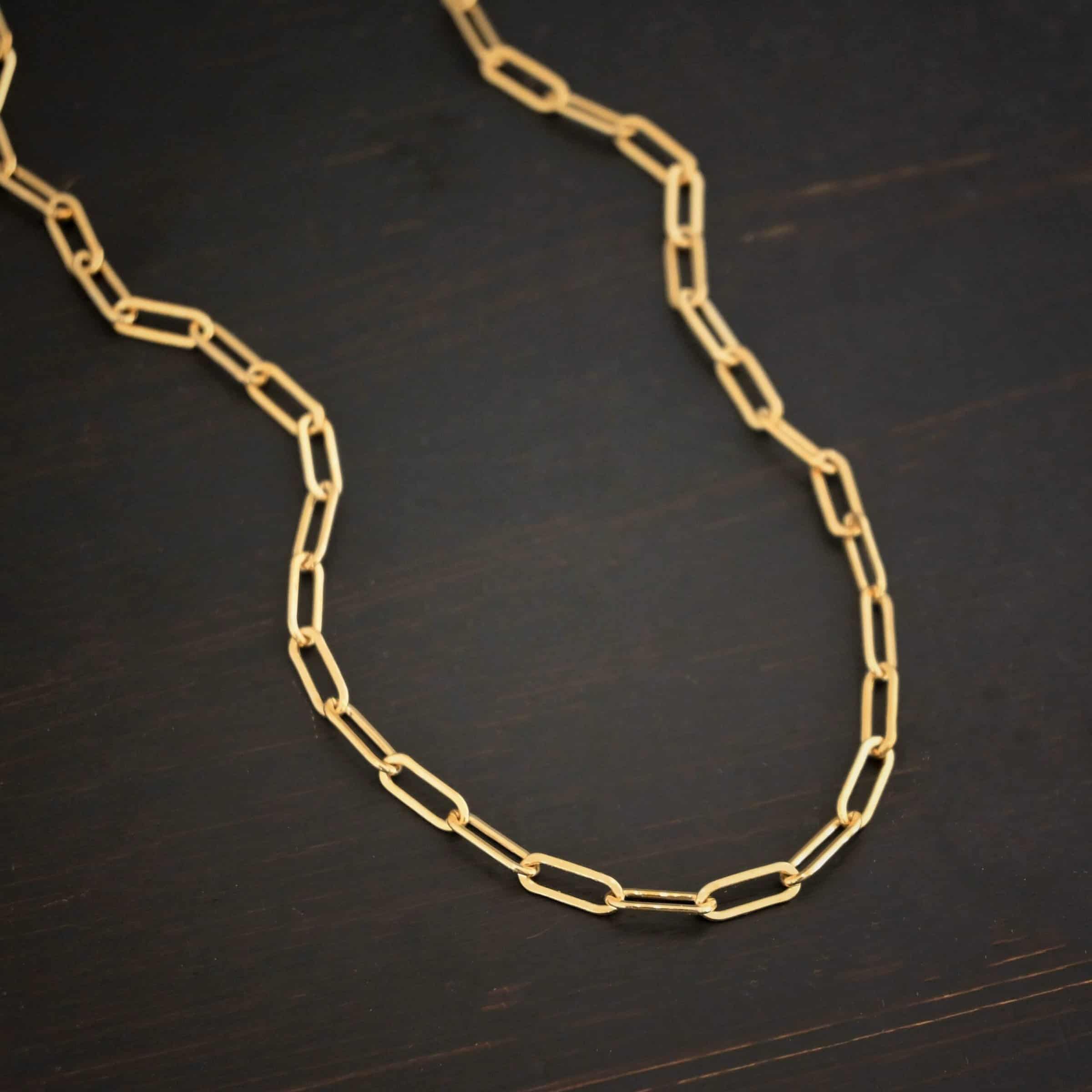 Lulu Link GF "Lulu Link" Chain as shown as gold filled. Links are 8.5x3x2mm. Chain is lying against a dark background.