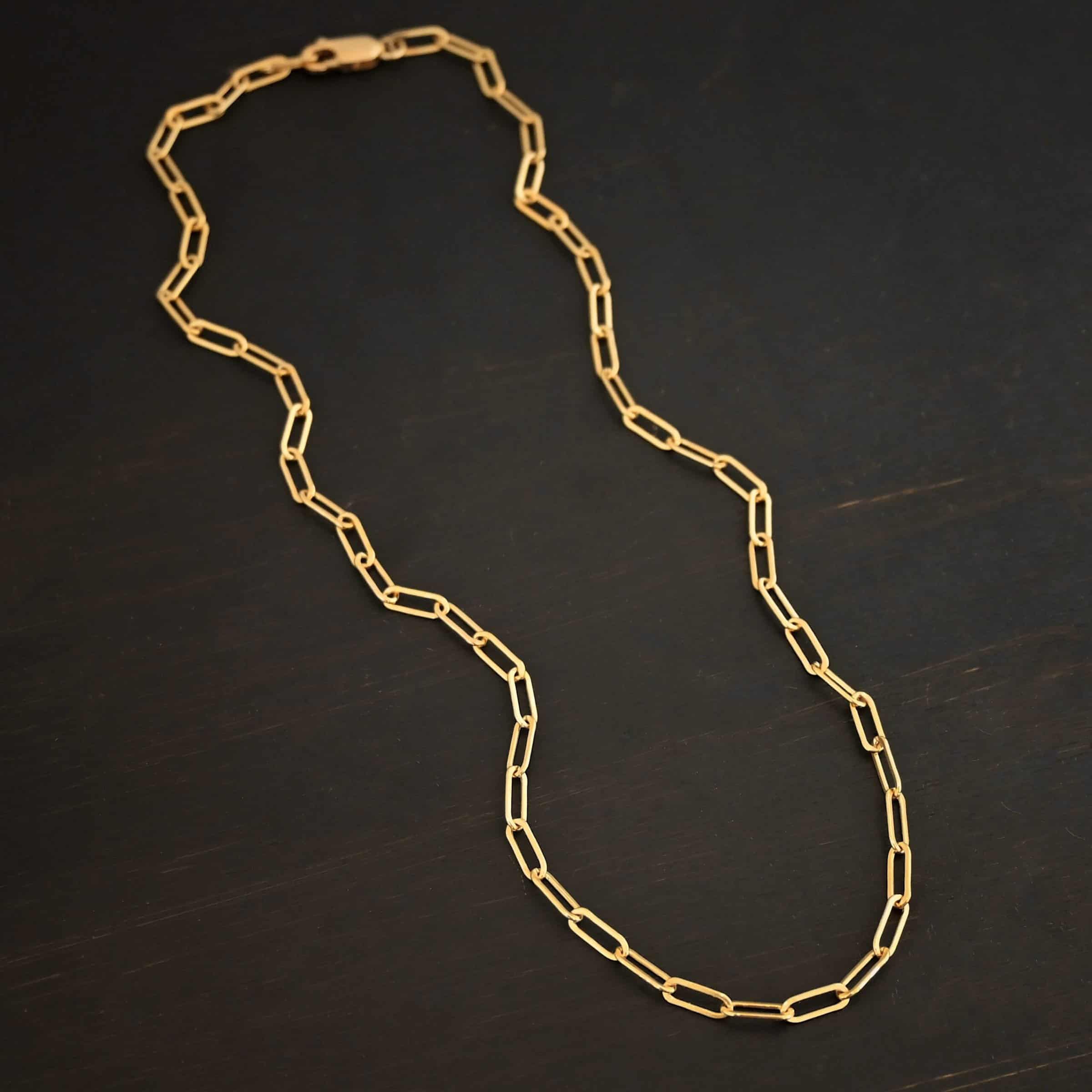 Lulu Link GF "Lulu Link" Chain as shown as gold filled. Links are 8.5x3x2mm. Chain is lying against a dark background.
