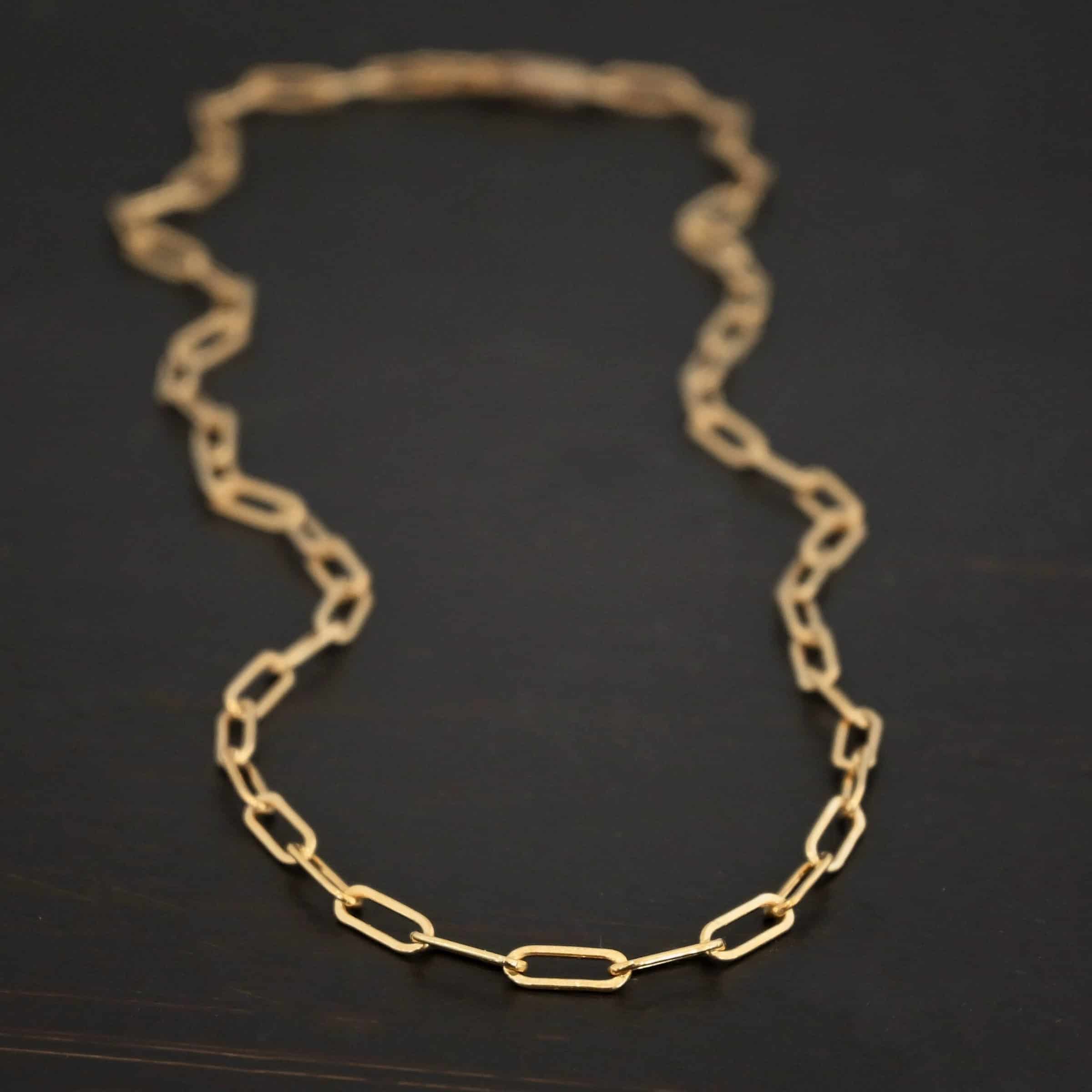 Lulu Link GF "Lulu Link" Chain as shown as gold filled. Links are 8.5x3x2mm. Chain is lying against a dark background.
