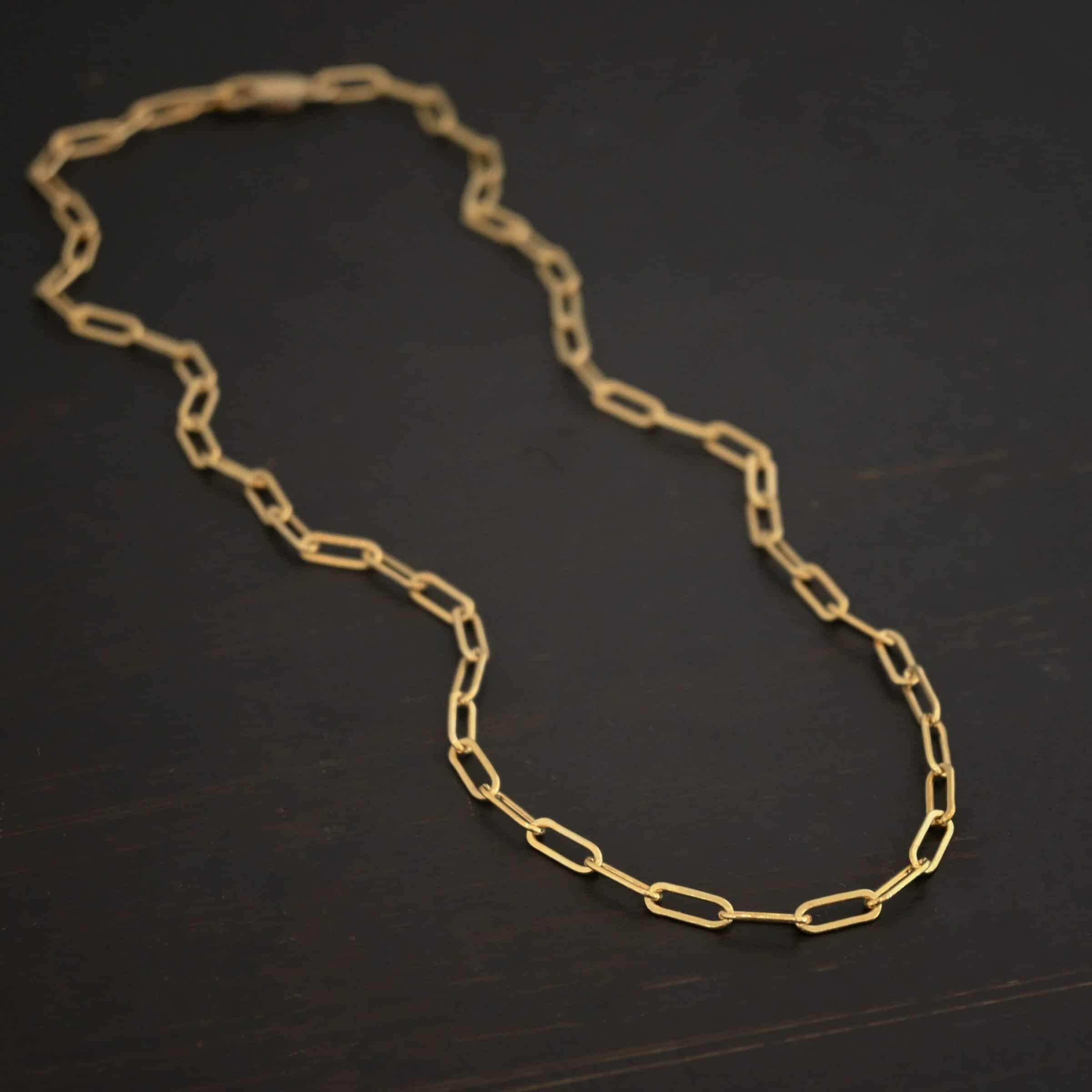 Lulu Link GF "Lulu Link" Chain as shown as gold filled. Links are 8.5x3x2mm. Chain is lying against a dark background.