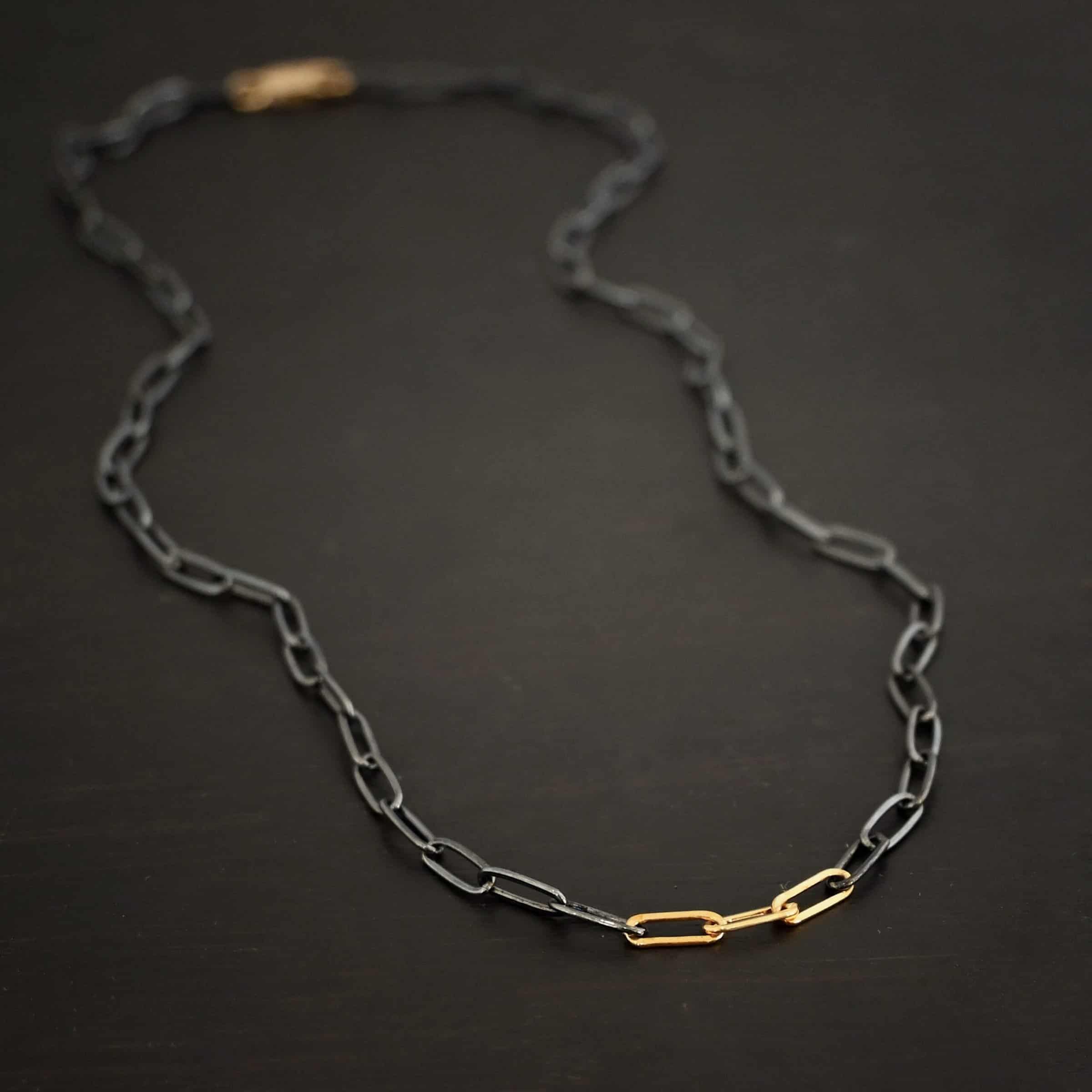 Lulu Link Silver & GF "Lulu Link" Chain as shown as oxidized and gold filled. Links are 8.5x3x2mm. Chain is lying against a dark background.