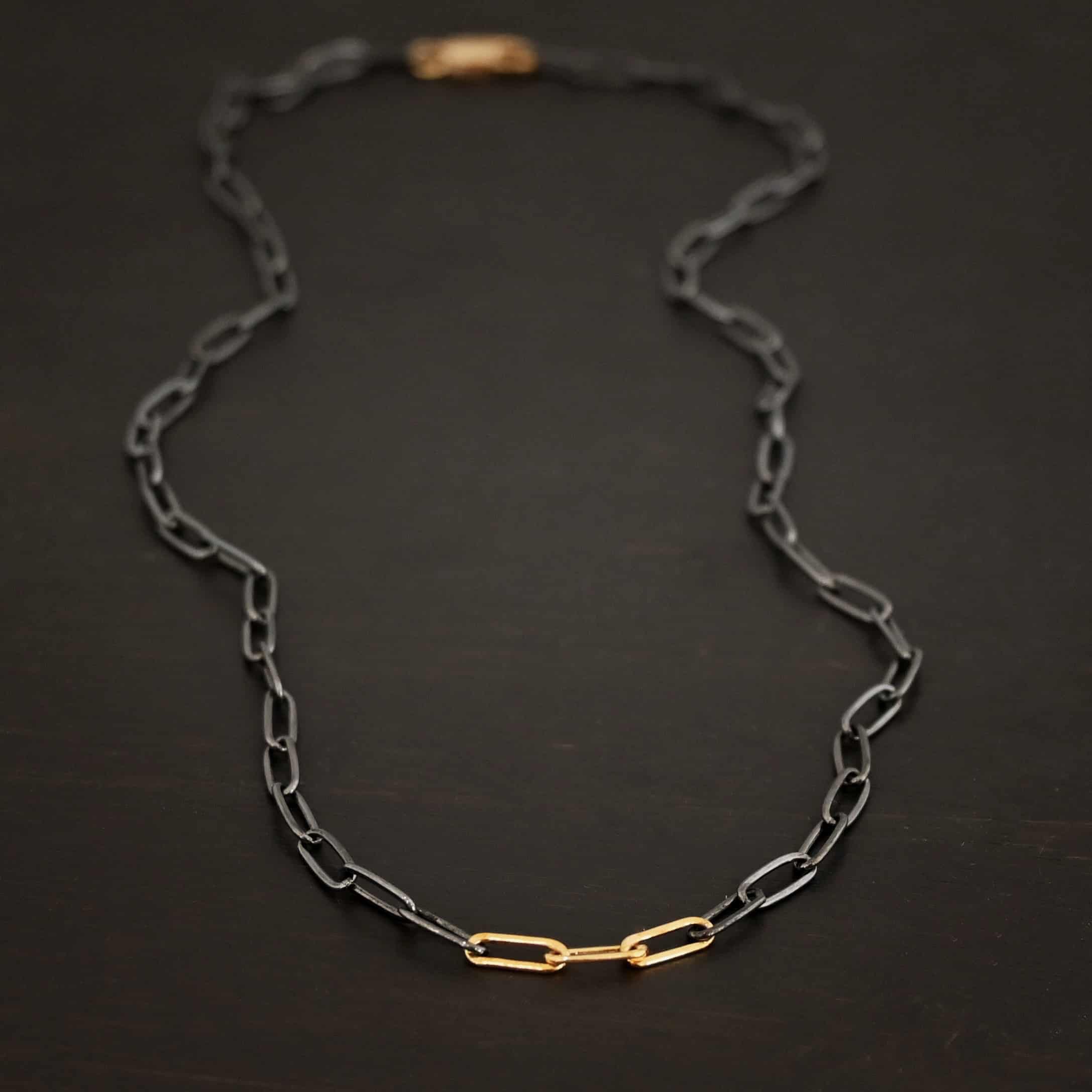 Lulu Link Silver & GF "Lulu Link" Chain as shown as oxidized and gold filled. Links are 8.5x3x2mm. Chain is lying against a dark background.