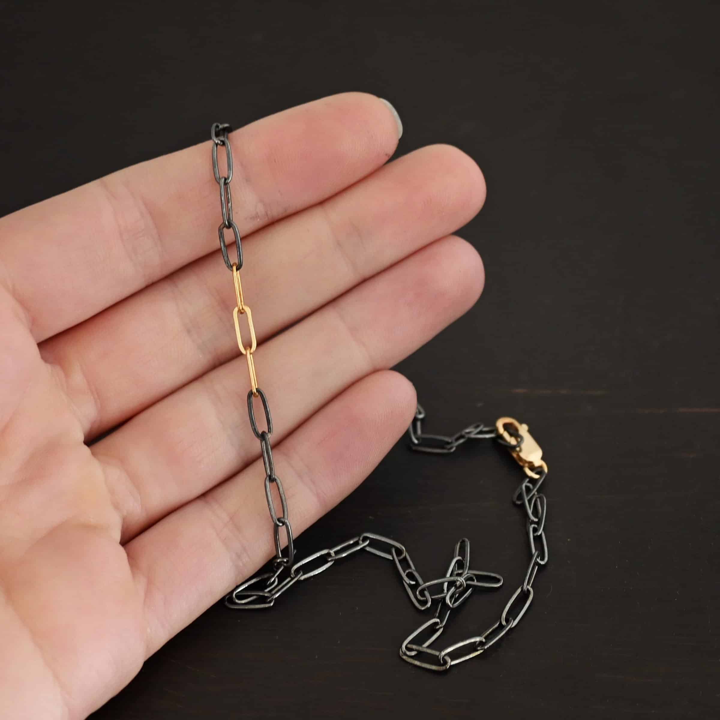 Lulu Link Silver & GF "Lulu Link" Chain as shown as oxidized and gold filled. Links are 8.5x3x2mm. Chain is lying against the fingertips of a hand to demonstrate size.