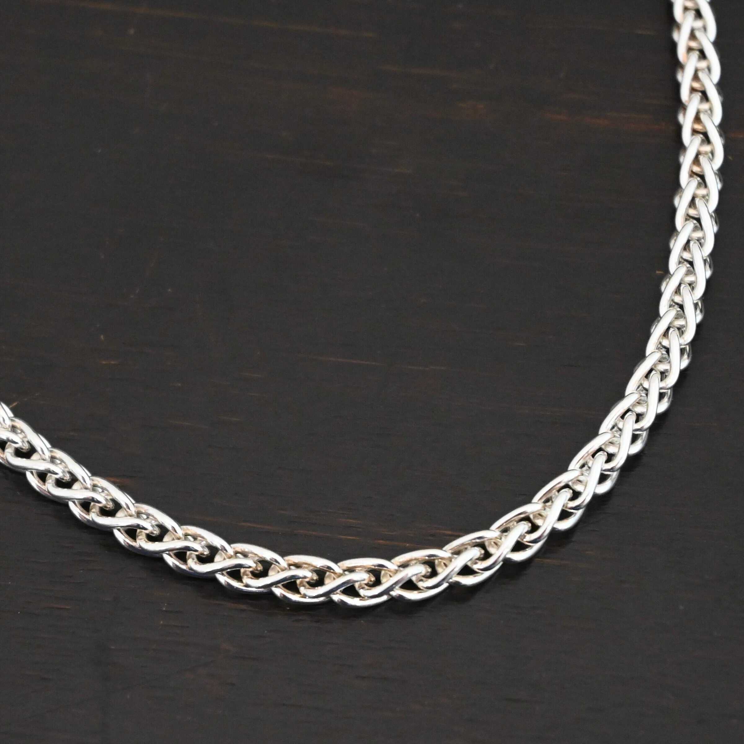 King Cobra Wheat Chain The "King Cobra" Wheat Chain. Chain is handmade out of sterling silver and woven together loosely. Each link is woven to another one and there are sterling silver end caps on each end of the chain. Chain has a lobster claw clasp and comes with a 3 inch extension. Chain is laying against a dark background. Chain is shown as shiny.