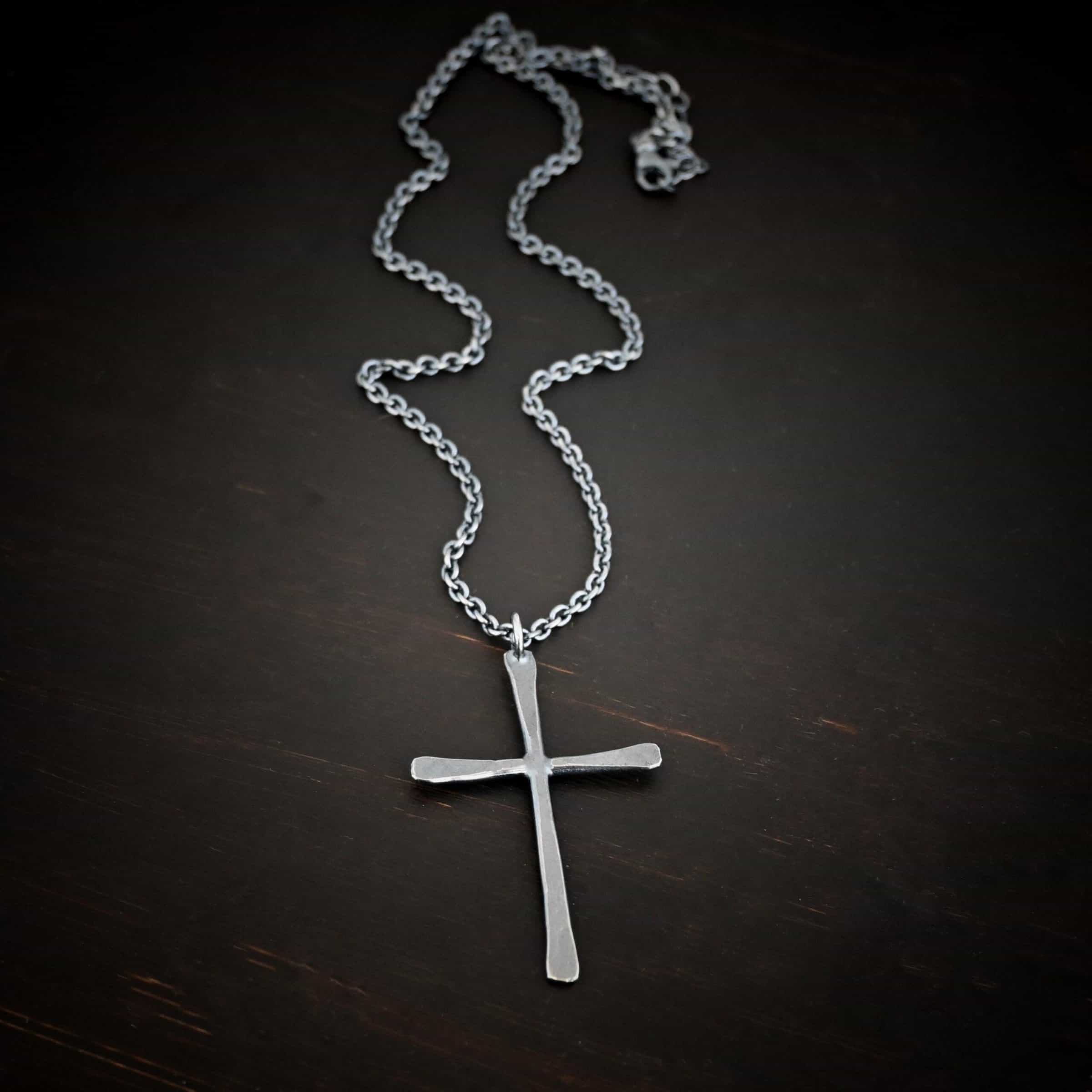 Ol Rugged Cross Necklace Photo of the "Ol' Rugged Cross" Necklace. Made out of sterling silver. There is a large cross that is hammered flat, but smooth. It is oxidized and has a loop soldered to the top of it. There is a chain that goes through the top of the necklace. Necklace is lying against a dark background.