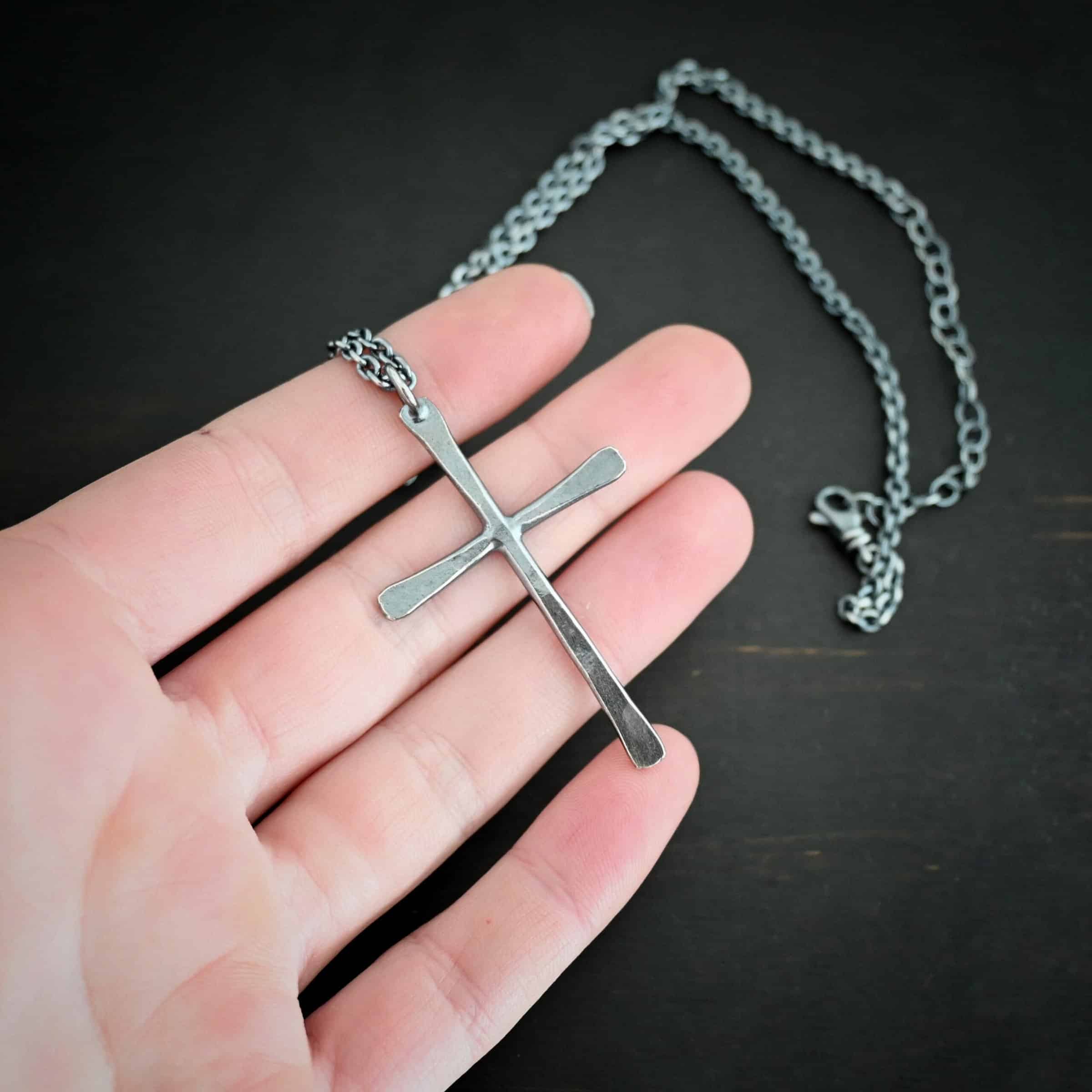 Ol Rugged Cross Necklace Photo of the "Ol' Rugged Cross" Necklace. Made out of sterling silver. There is a large cross that is hammered flat, but smooth. It is oxidized and has a loop soldered to the top of it. There is a chain that goes through the top of the necklace. Necklace is lying against the fingertips of a hand.
