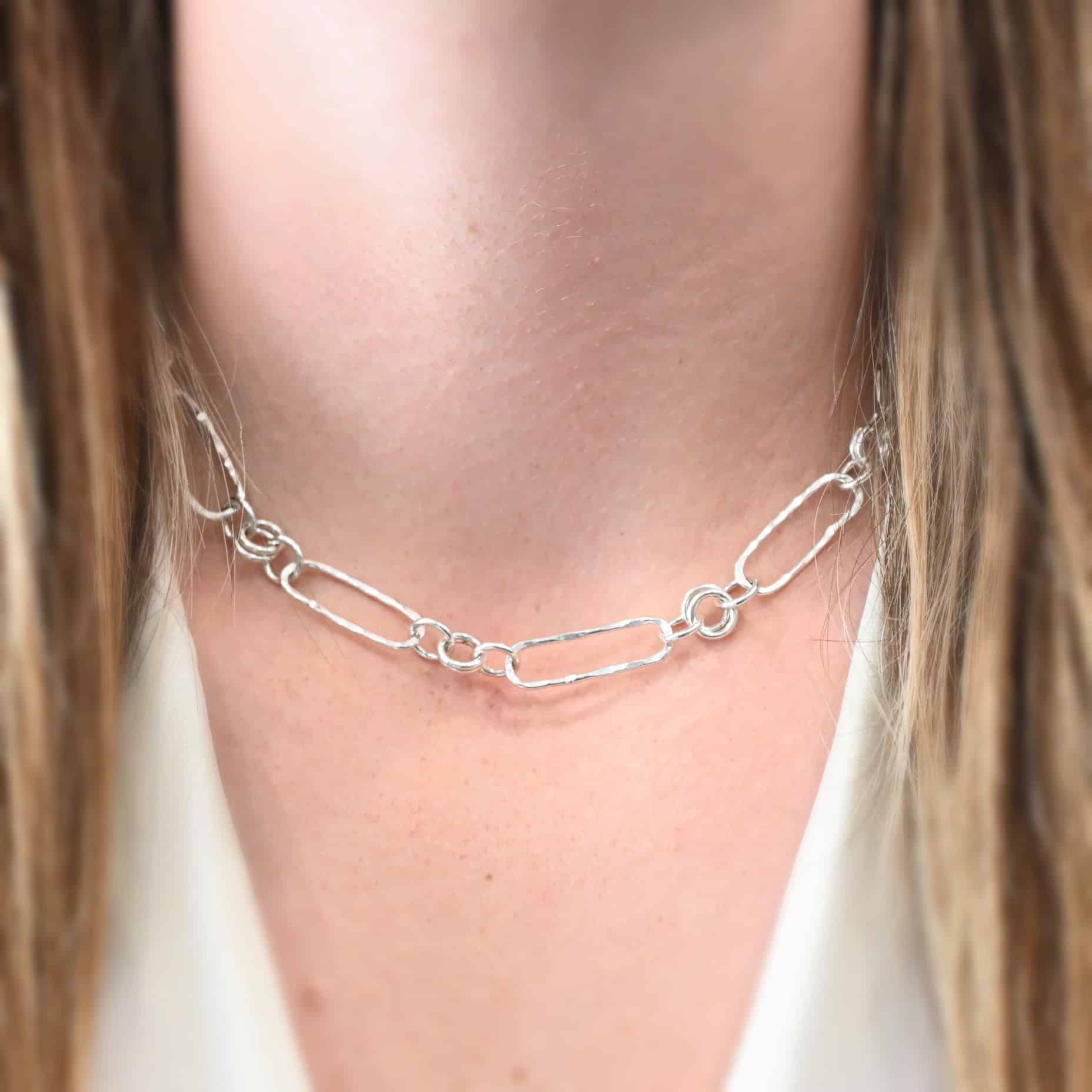 "Bekah Chain" as shown on a model. Model is wearing an 16 inch shiny Bekah chain. Model has on a white v-neck shirt.