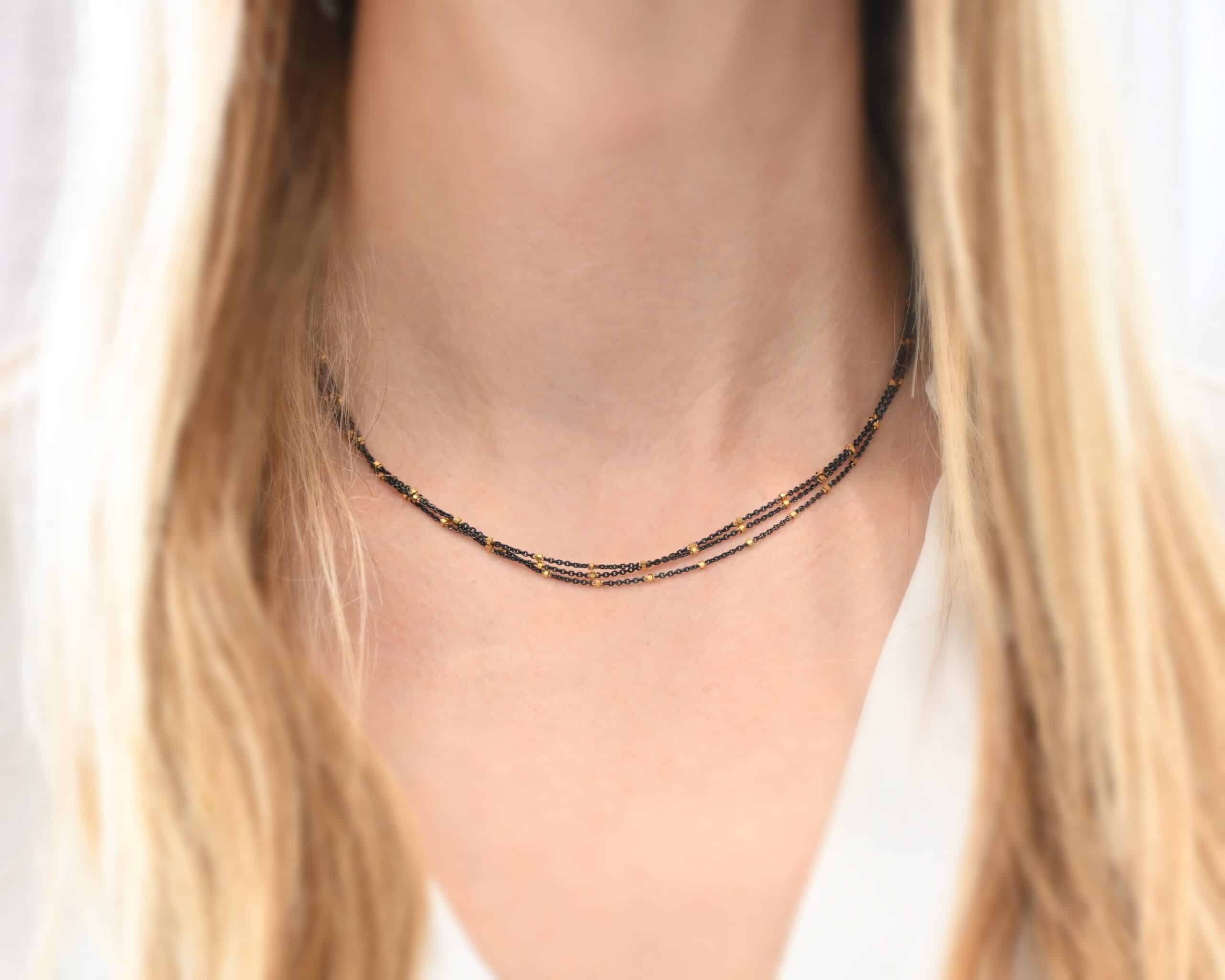 Night in Paris Chain "Night In Paris" Chain as shown up close on a model. Sterling Silver & 14k yellow gold filled beads that are 1.5mm thick. The chain is 1.2mm thick. Chain has three separate strands that meet at the back to make one chain. Chain is shown at 16" on a model.