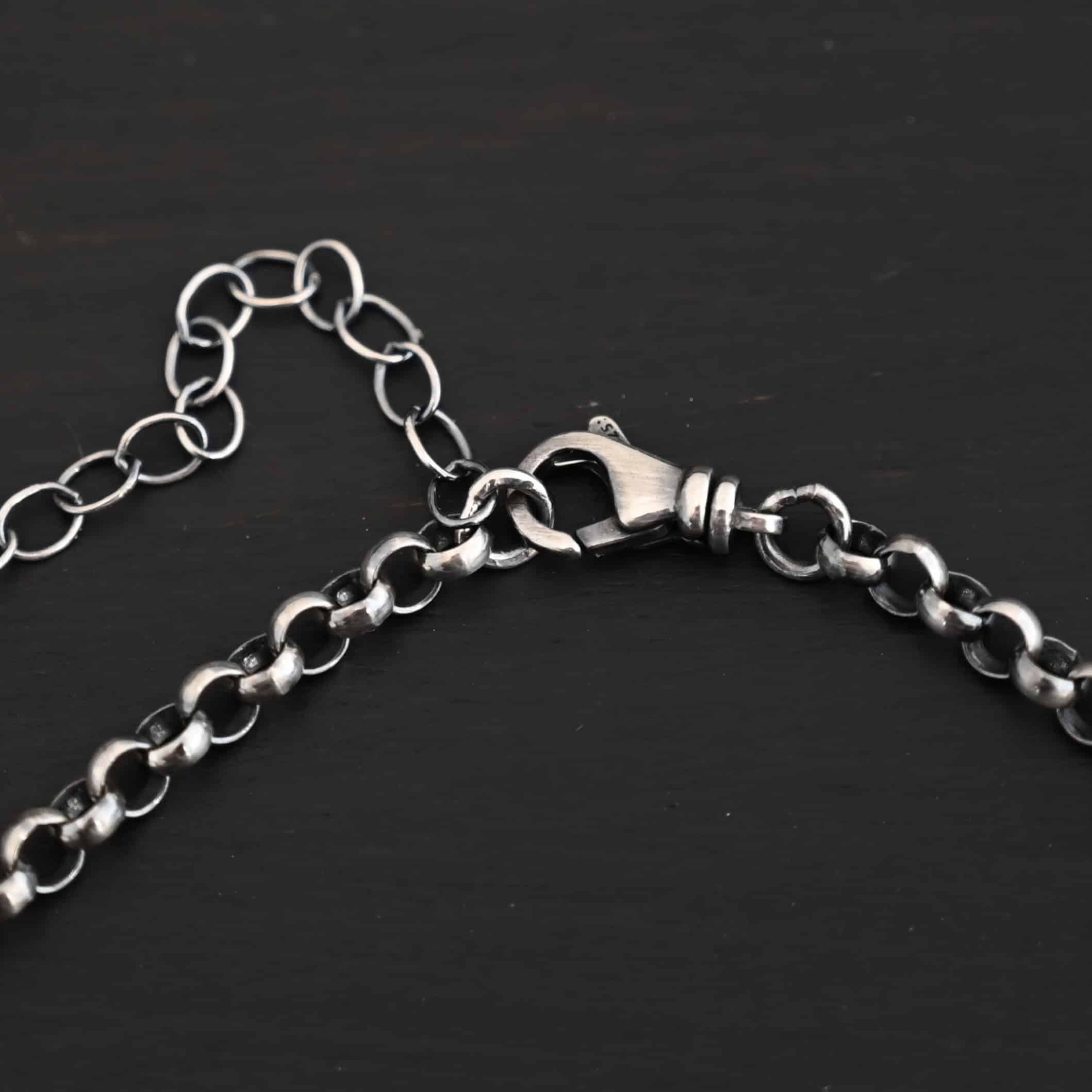 Close up of the sterling silver oxidized Roxy Rolo Chain that is made with small circular links with an emphasis on the lobster claw clasp of the chain