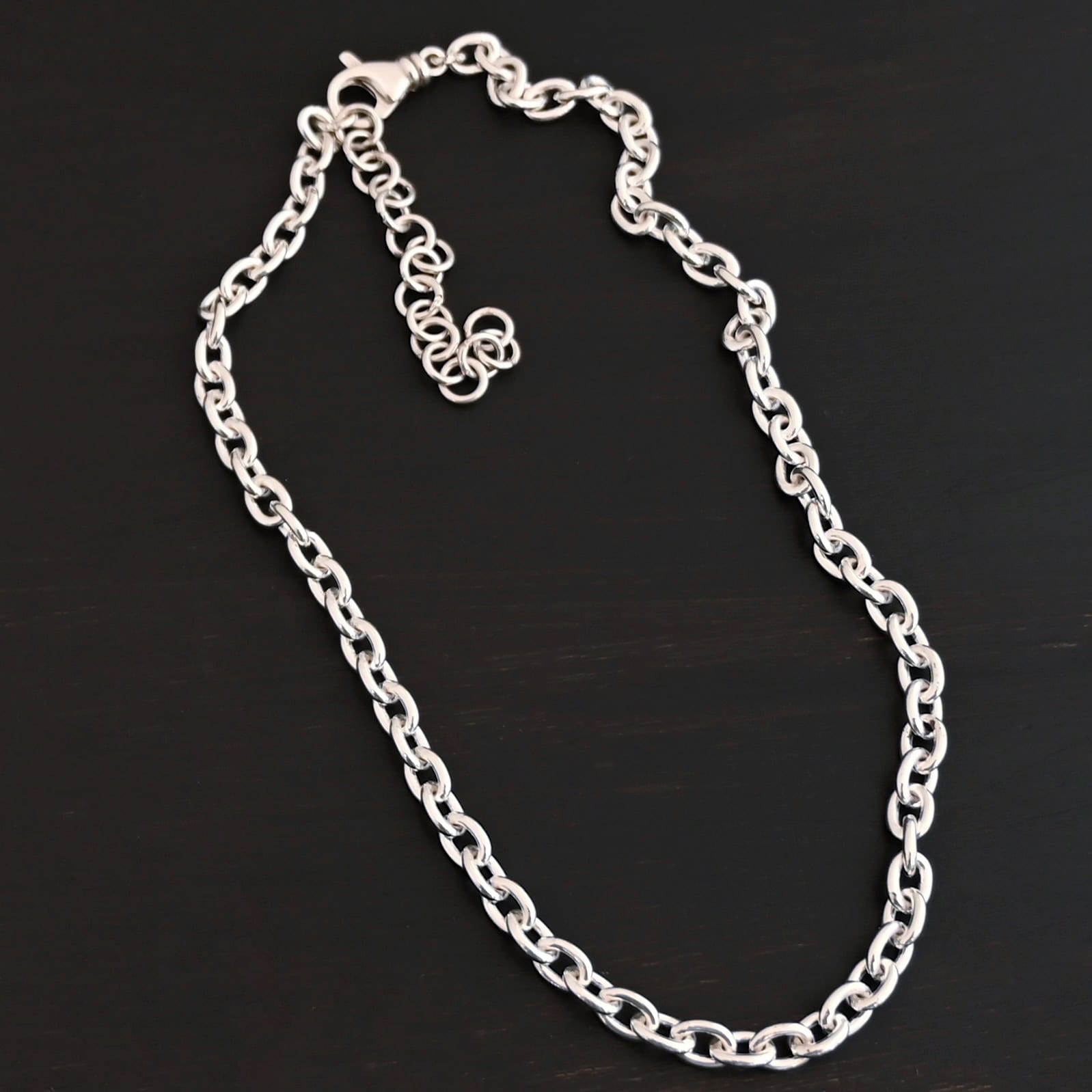 Shiny sterling silver Georgia Chain with thick oval links that measure 8x6mmx1.7mm thick. Chain is resting against a dark background.