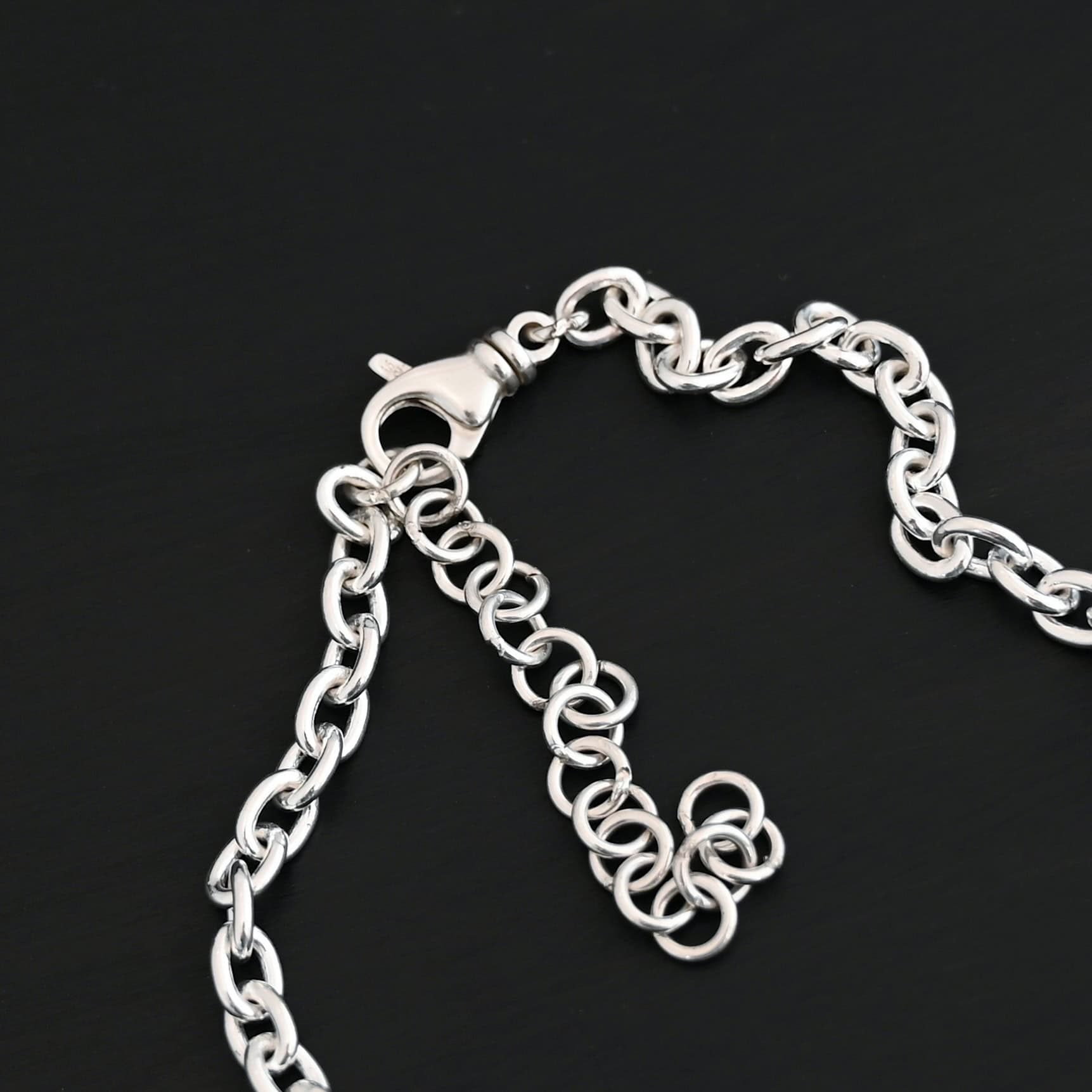 Shiny sterling silver Georgia Chain with thick oval links that measure 8x6mmx1.7mm thick. Chain is resting against a dark background.