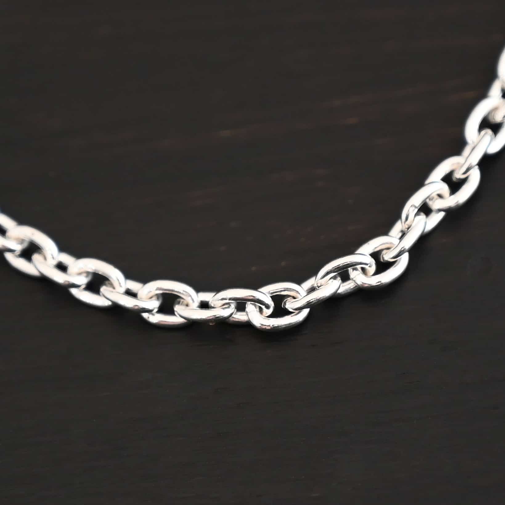Close up of shiny sterling silver Lauren chain with oval links laying against a dark background. Links measure 5x4mmx1mm thick.