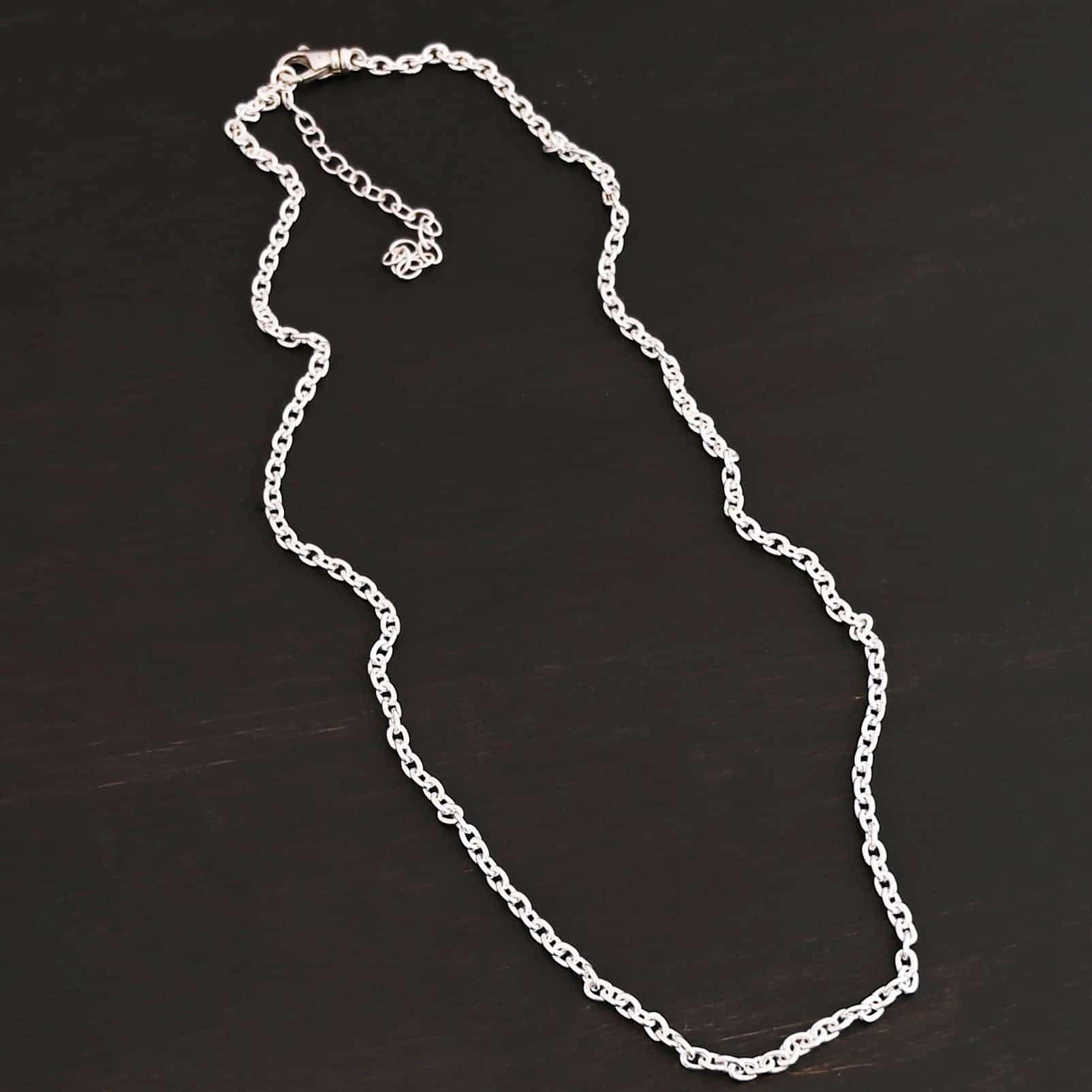 Shiny sterling silver Lauren chain with oval links laying against a dark background. Links measure 5x4mmx1mm thick.