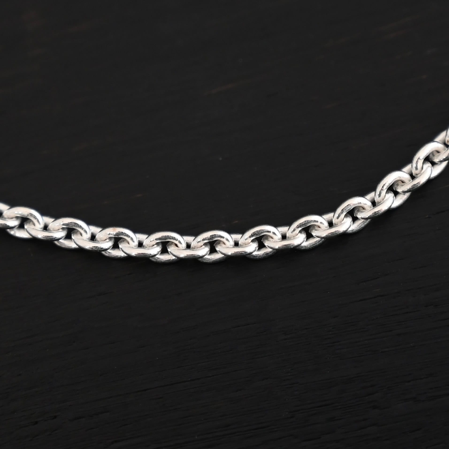 Savannah Chain Shiny Close up of a shiny sterling silver Savannah Chain with circle links that is laying against a dark background. Links measure 3x2mmx.7mm thick.