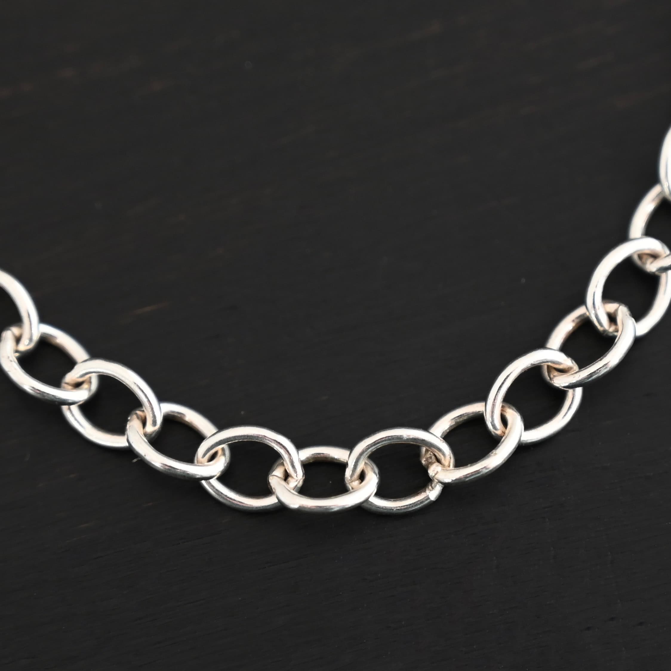 Jay Chain Shiny A close-up of the shiny sterling silver Jay chain set against a dark black background. Links measure 7.2×5.7mm.