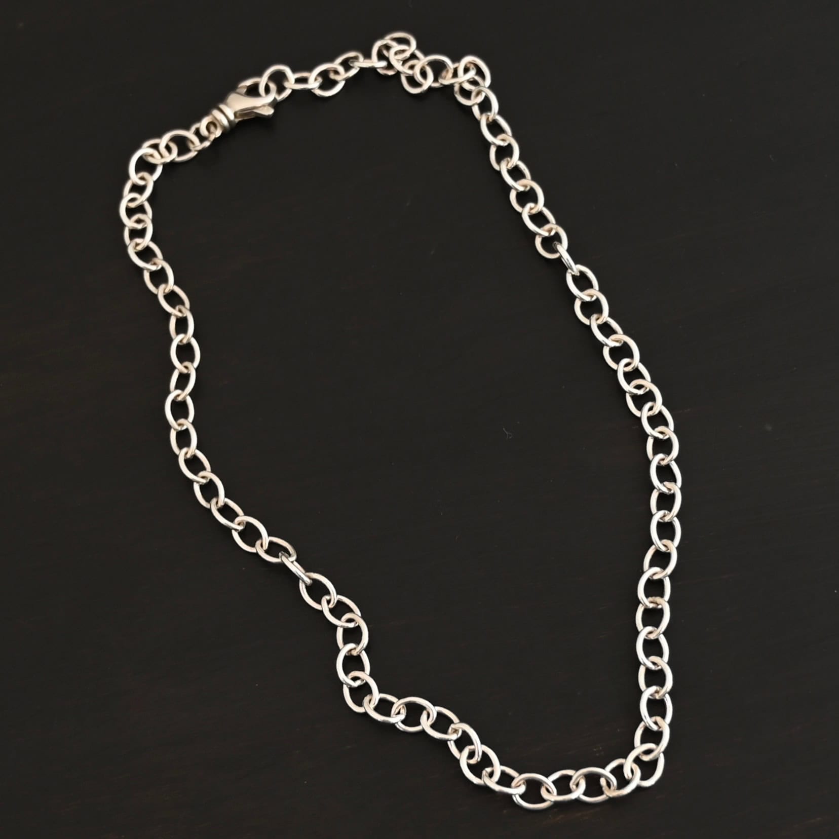 Jay Chain Shining Sterling silver Jay chain with circular links that measure 7.2×5.7mm set against a dark black background.