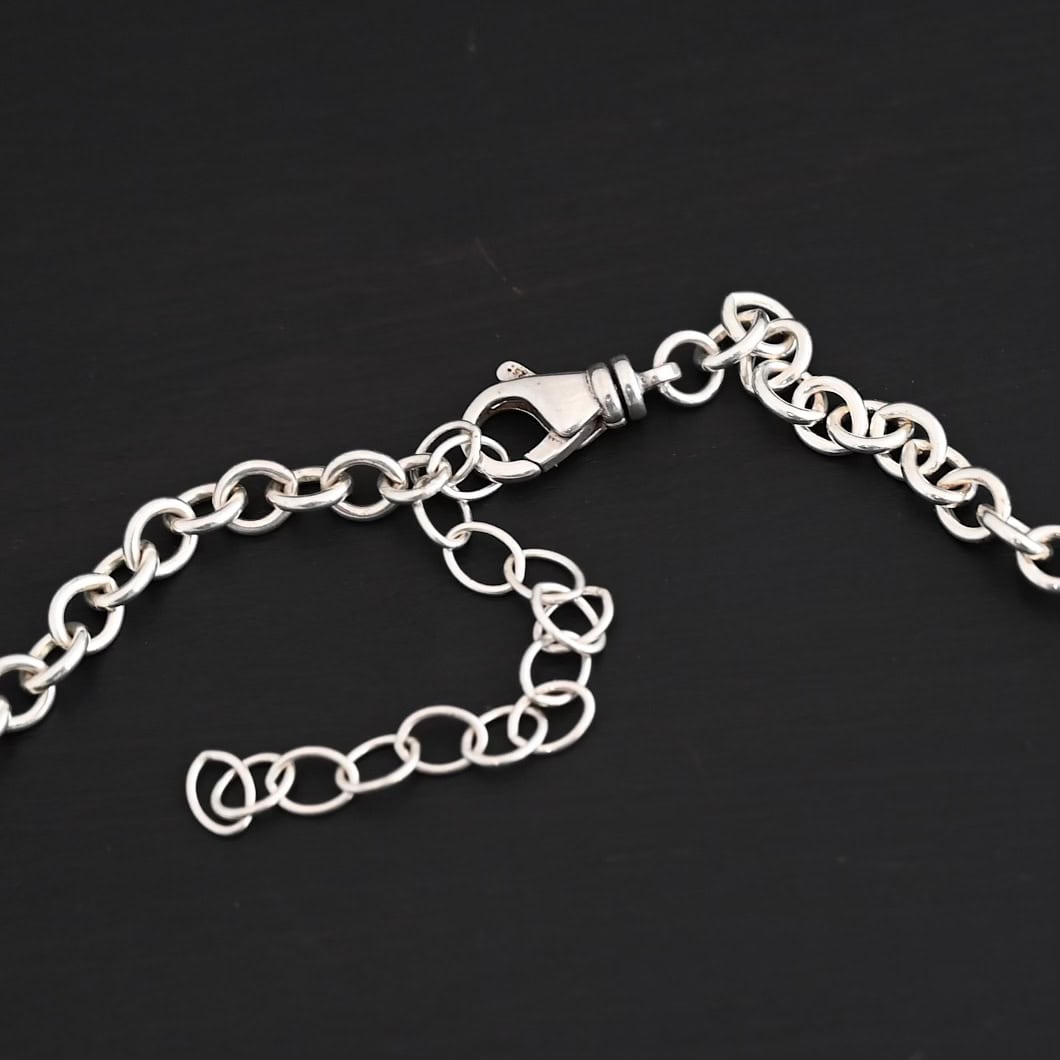 Shiny sterling silver Joy chain with circular links laying on a dark background with the lobster claw clasp showing as the main focus. Links measure 6.5×5.4mm.