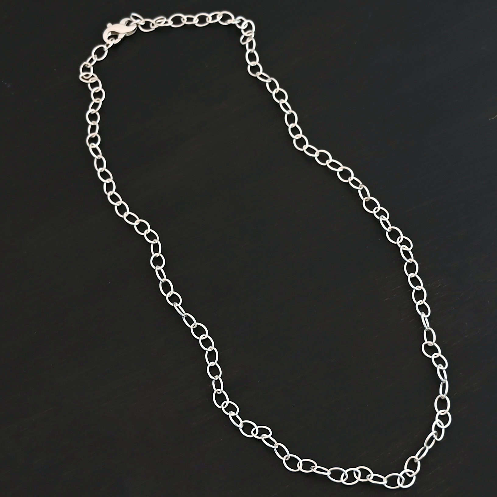 Willow Chain Shiny Sterling silver shiny Willow oval chain shown on dark background. Oval links measure 6.5×4.7mm