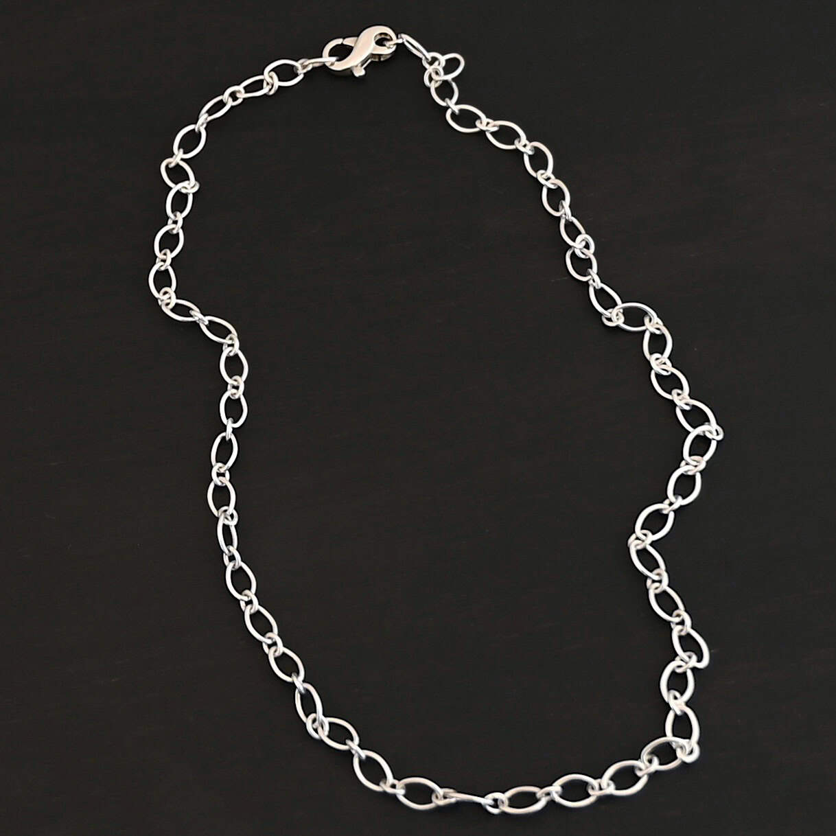 Allie Chain Shiny Sterling silver shiny Allie oval chain shown on dark background. Oval links measure 7×4.6mm.