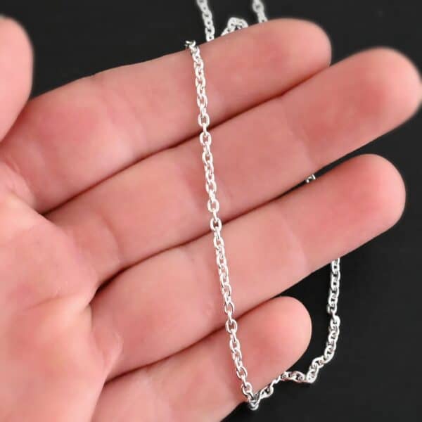 Shiny sterling silver Savannah Chain with circle links that is laying on a hand that is resting against a dark background. Links measure 3x2mmx.7mm thick.