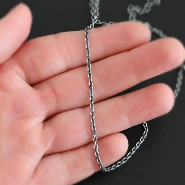 Oxidized sterling silver Savannah Chain with circle links that is laying on a hand that is resting against a dark background. Links measure 3x2mmx.7mm thick.