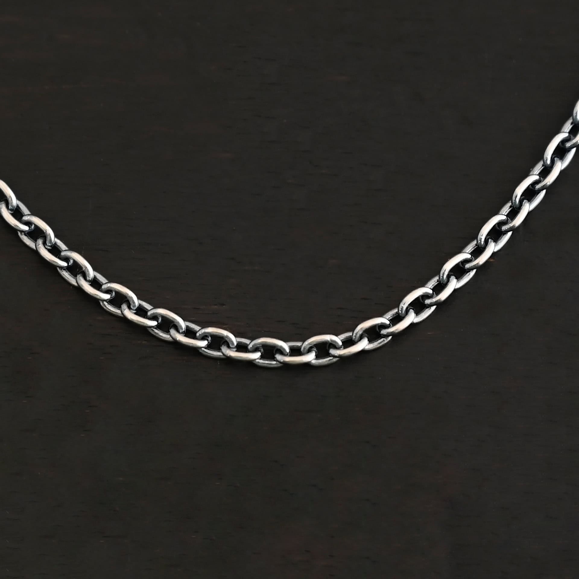Maria Chain Oxidized Close up of an oxidized sterling silver Maria Chain with circle links that is laying on a dark background. Links are 4x3mmx.8mm thick.