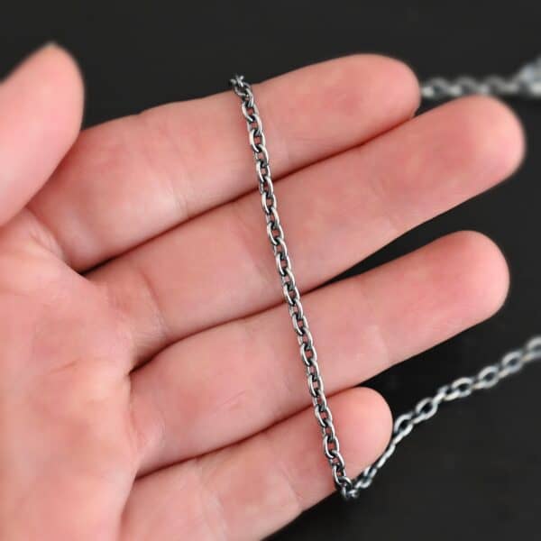 Oxidized sterling silver Maria chain with circle links that is laying on a hand which is resting against a dark background. Links are 4x3mmx.8mm thick.
