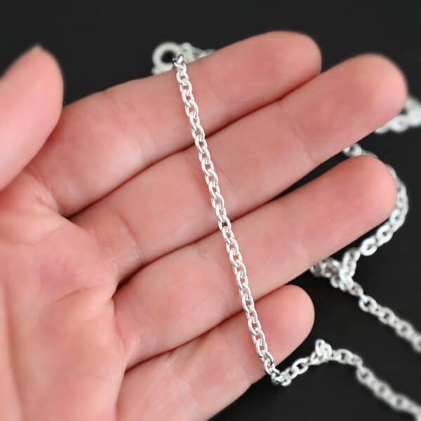 Shiny sterling silver Maria chain with circle links that is laying on a hand which is resting against a dark background. Links are 4x3mmx.8mm thick.