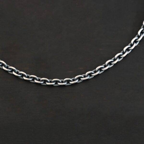 Close up of an oxidized sterling silver Joan chain with oval links that is resting against a dark background. Links are 6x5mmx1.2mm thick.