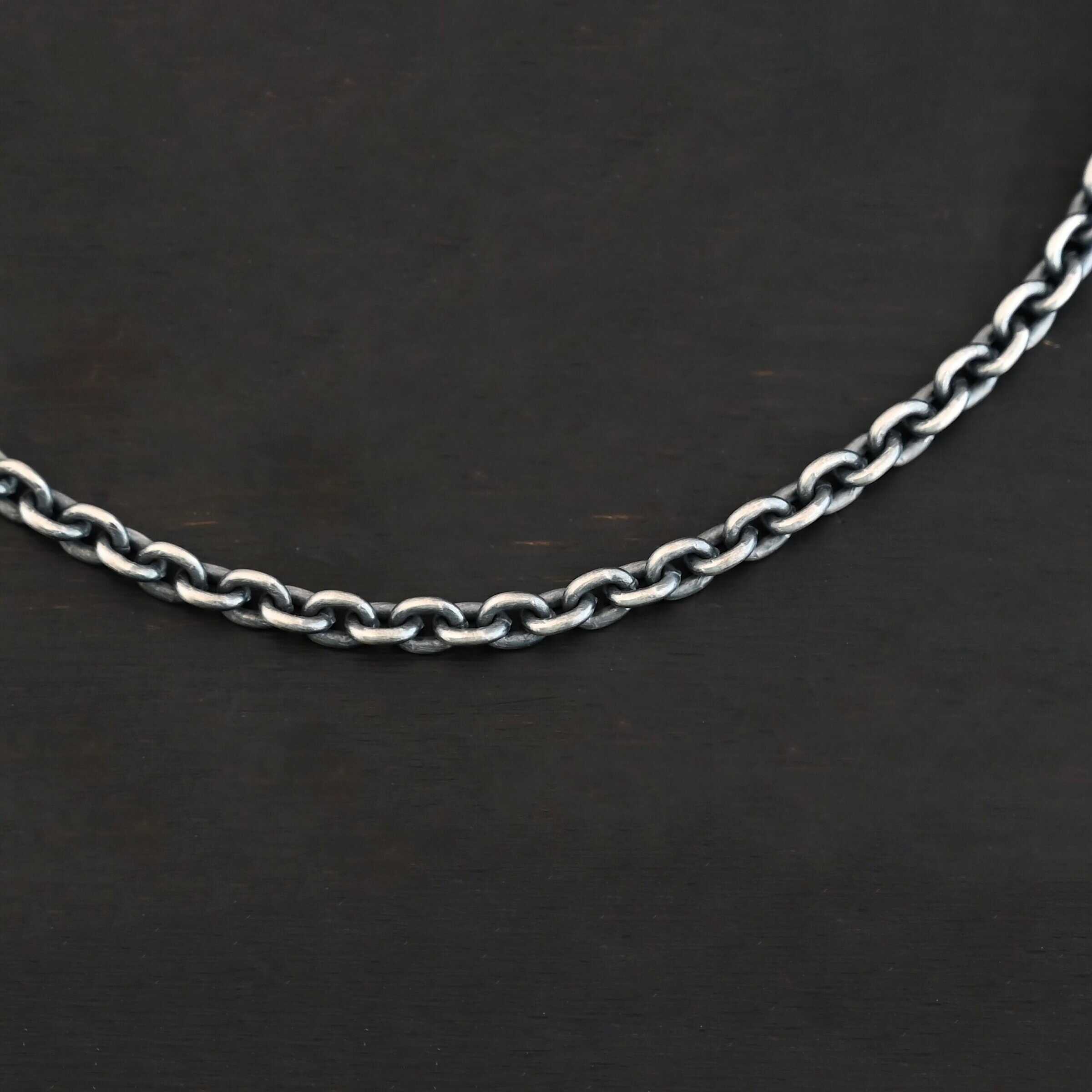 Joan Chain Close up of an oxidized sterling silver Joan chain with oval links that is resting against a dark background. Links are 6x5mmx1.2mm thick.