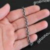 Oxidized sterling silver Joan Chain with oval links that are 6x5mmx1.2mm thick lying against a hand that is resting on a dark background.