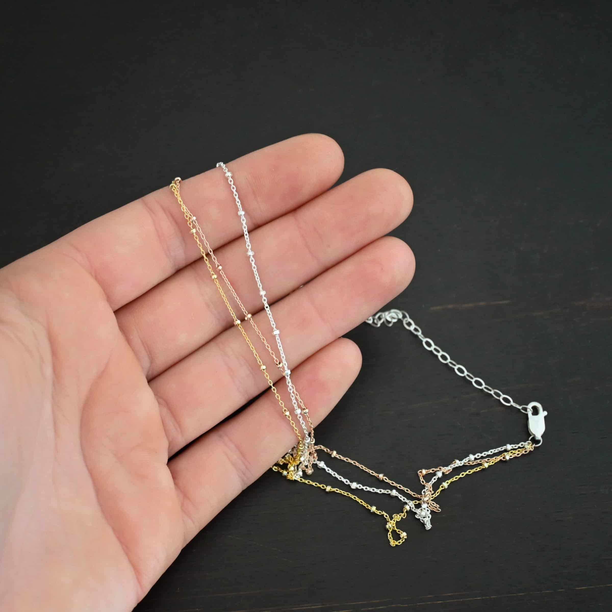 Champagne in Paris shiny "Champagne In Paris" Chain as shown up close. shiny Sterling Silver, 14K Rose Gold Filled, & 14K Yellow Gold Filled chain 1.2mm thick. Chain is lying against the fingertips of a hand to demonstrate thickness.