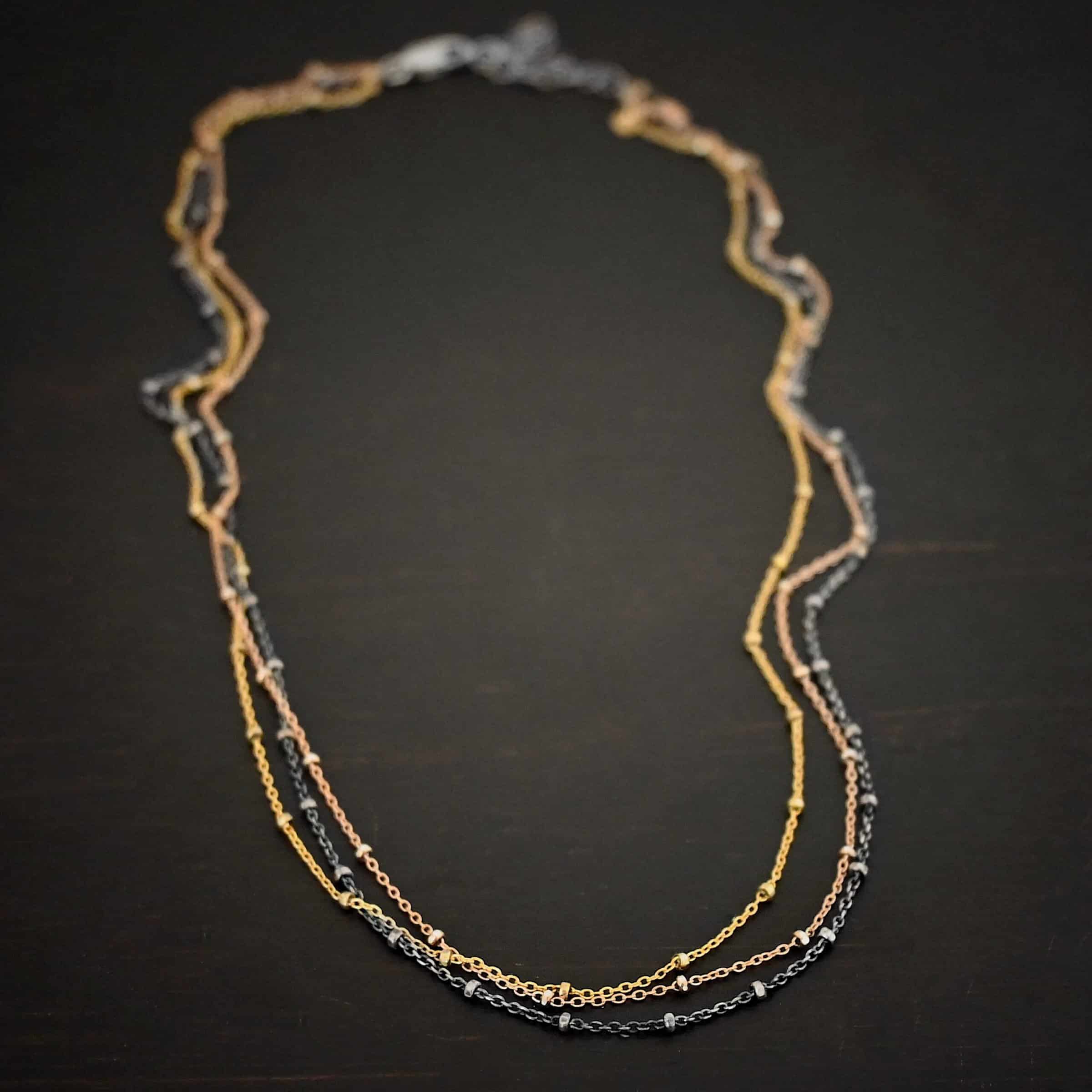 Champagne in Paris ox "Champagne In Paris" Chain as shown up close. oxidized Sterling Silver, 14K Rose Gold Filled, & 14K Yellow Gold Filled chain 1.2mm thick. Chain is shown against a dark background.