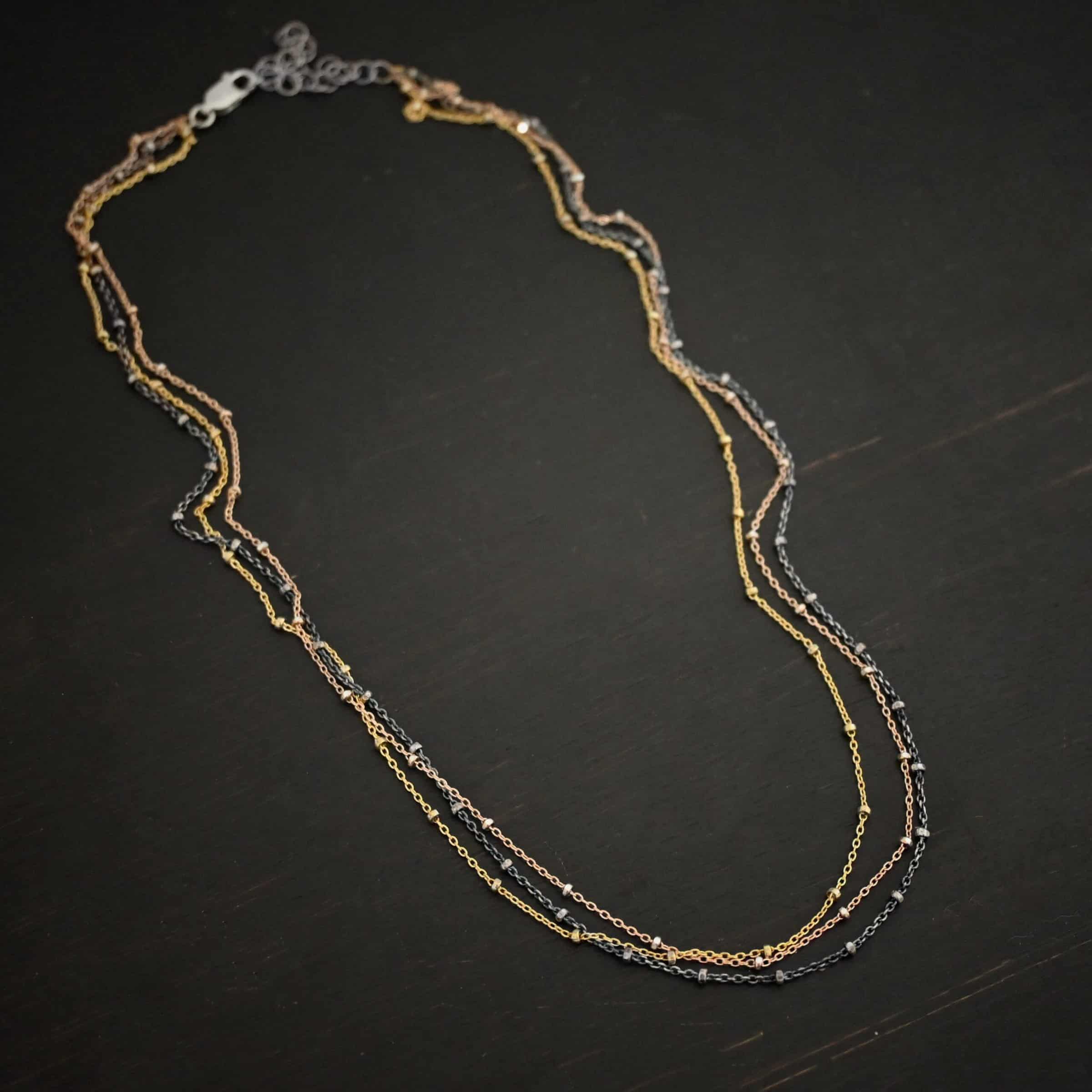 Champagne in Paris ox "Champagne In Paris" Chain as shown up close. oxidized Sterling Silver, 14K Rose Gold Filled, & 14K Yellow Gold Filled chain 1.2mm thick. Chain is shown against a dark background.