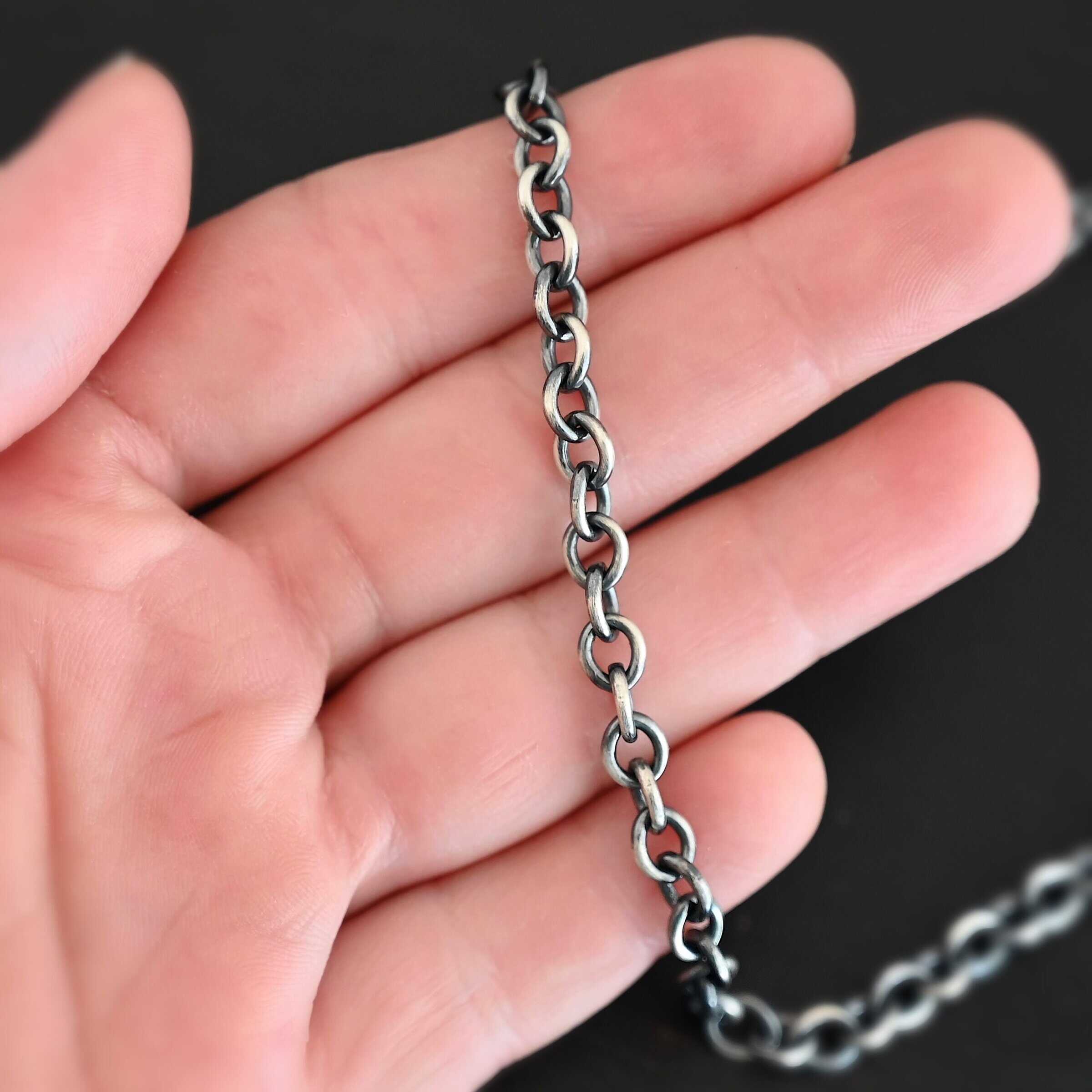 Oxidized sterling silver Joy chain with circular links laying on a hand that is resting against a dark background. Links measure 6.5×5.4mm.