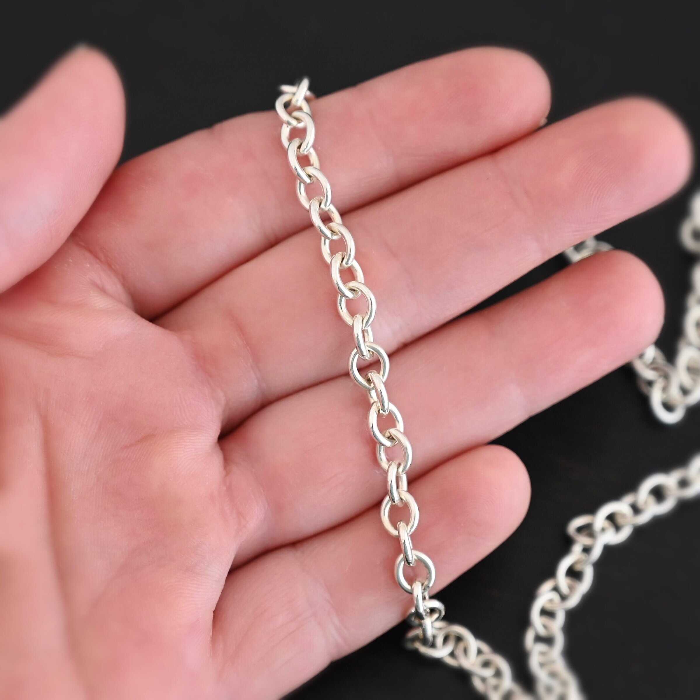 Shiny sterling silver Joy chain with circular links laying on a hand that is resting against a dark background. Links measure 6.5×5.4mm.