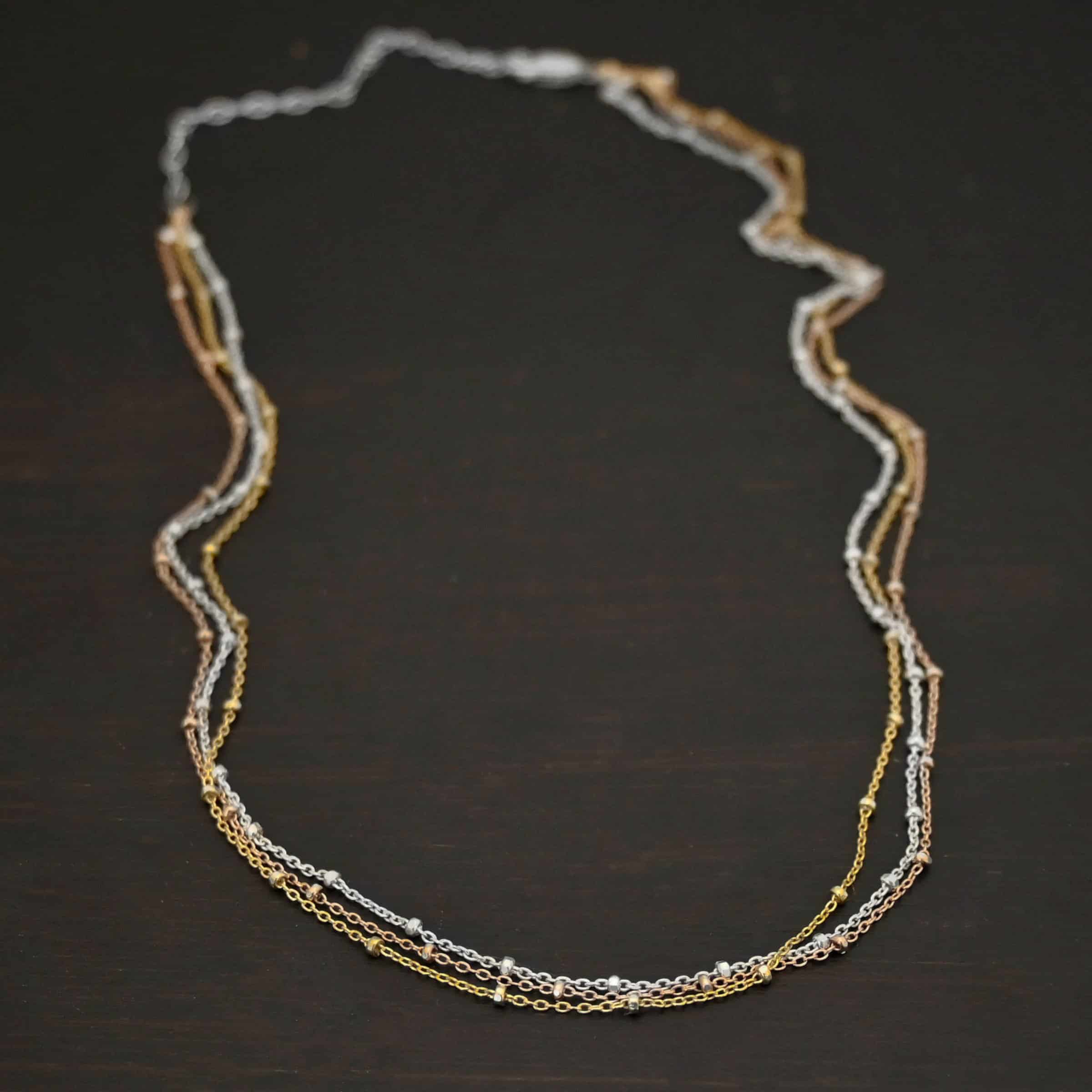 Champagne in Paris shiny "Champagne In Paris" Chain as shown up close. shiny Sterling Silver, 14K Rose Gold Filled, & 14K Yellow Gold Filled chain 1.2mm thick. Chain is shown against a dark background.