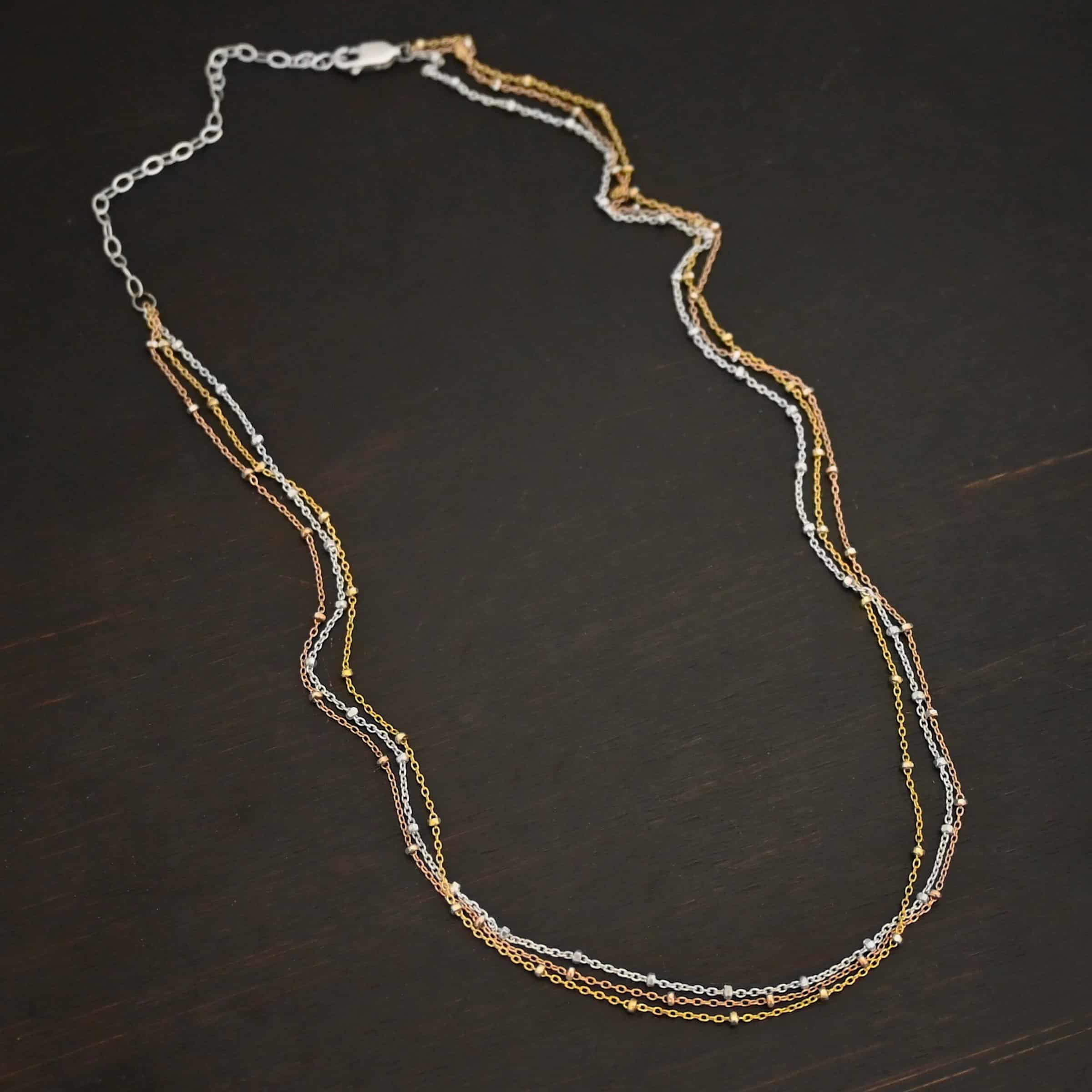 Champagne in Paris shiny "Champagne In Paris" Chain as shown up close. shiny Sterling Silver, 14K Rose Gold Filled, & 14K Yellow Gold Filled chain 1.2mm thick. Chain is shown against a dark background.