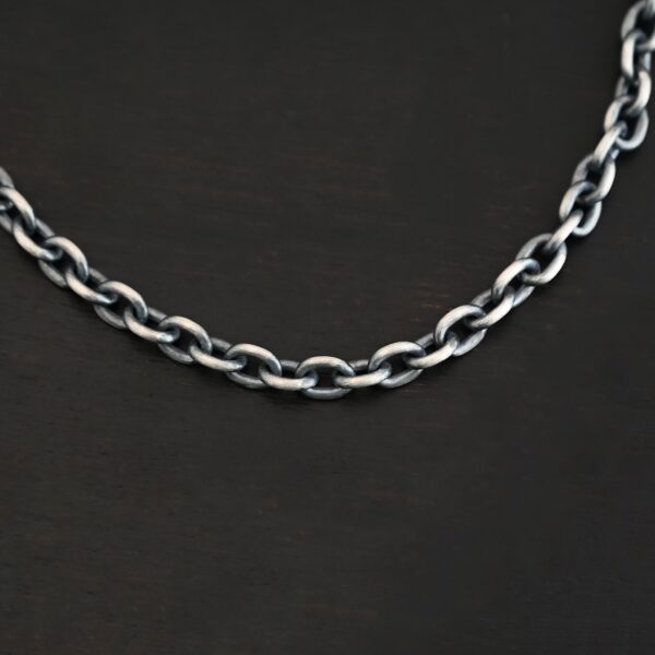 Close up of Georgia Chain that is oxidized sterling silver and has thick oval links that measure 8x6mmx1.7mm thick. Chain is resting against a dark background.