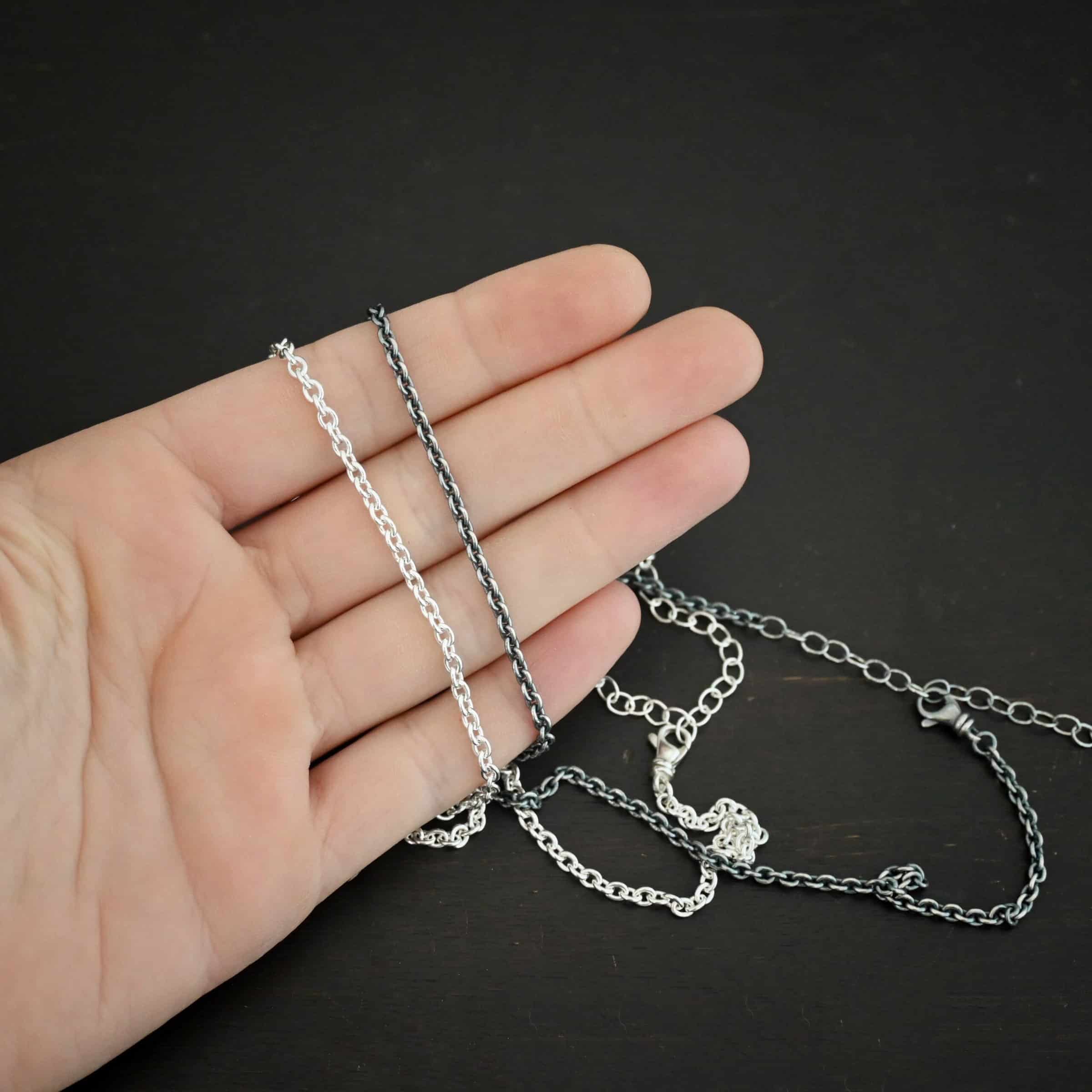 Maria Chain Shiny and oxidized sterling silver Maria chain with circle links that is laying on a hand which is resting against a dark background. Links are 4x3mmx.8mm thick.